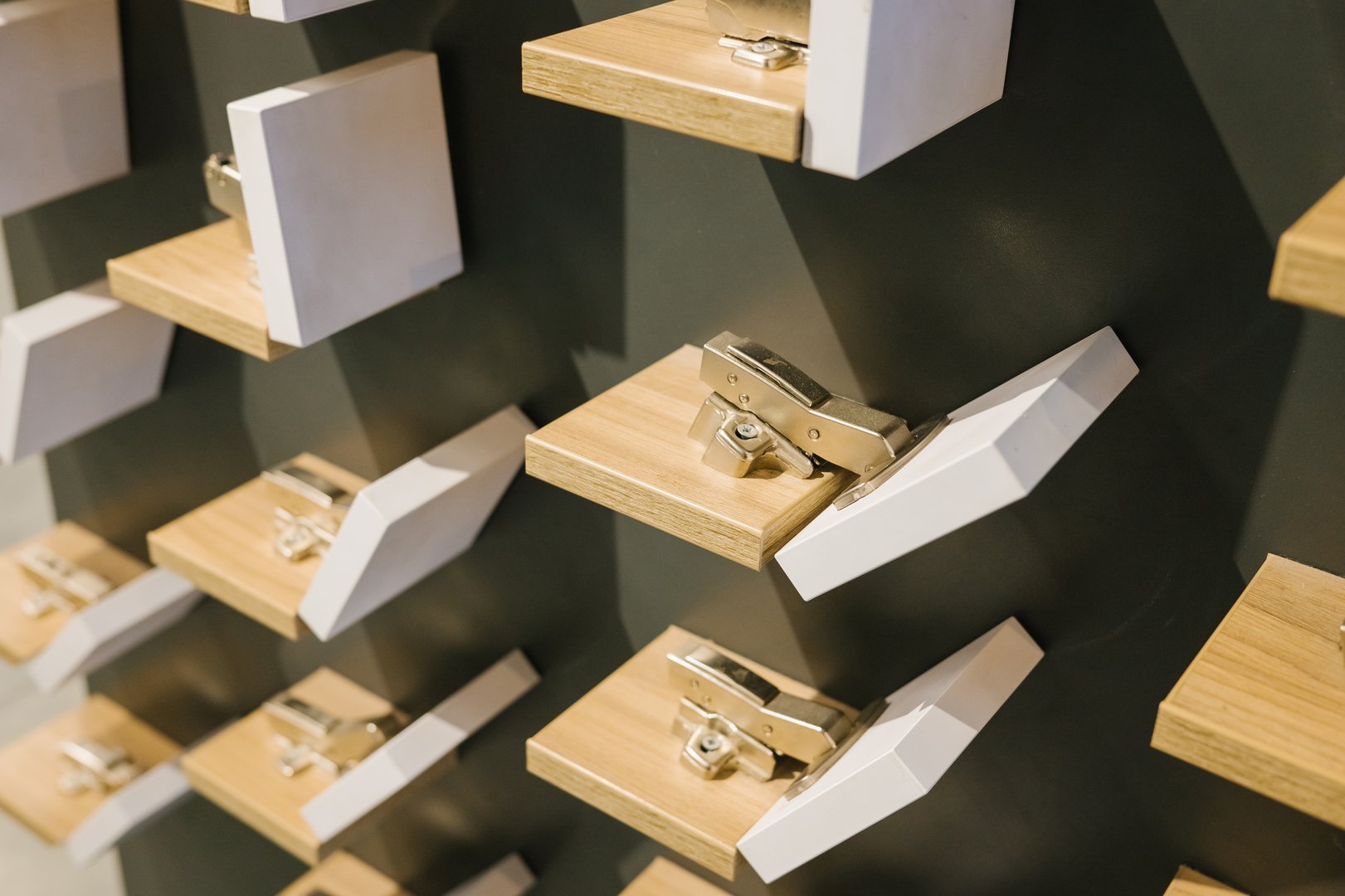 Wall display of cabinet hinges on wooden blocks in hardware store.