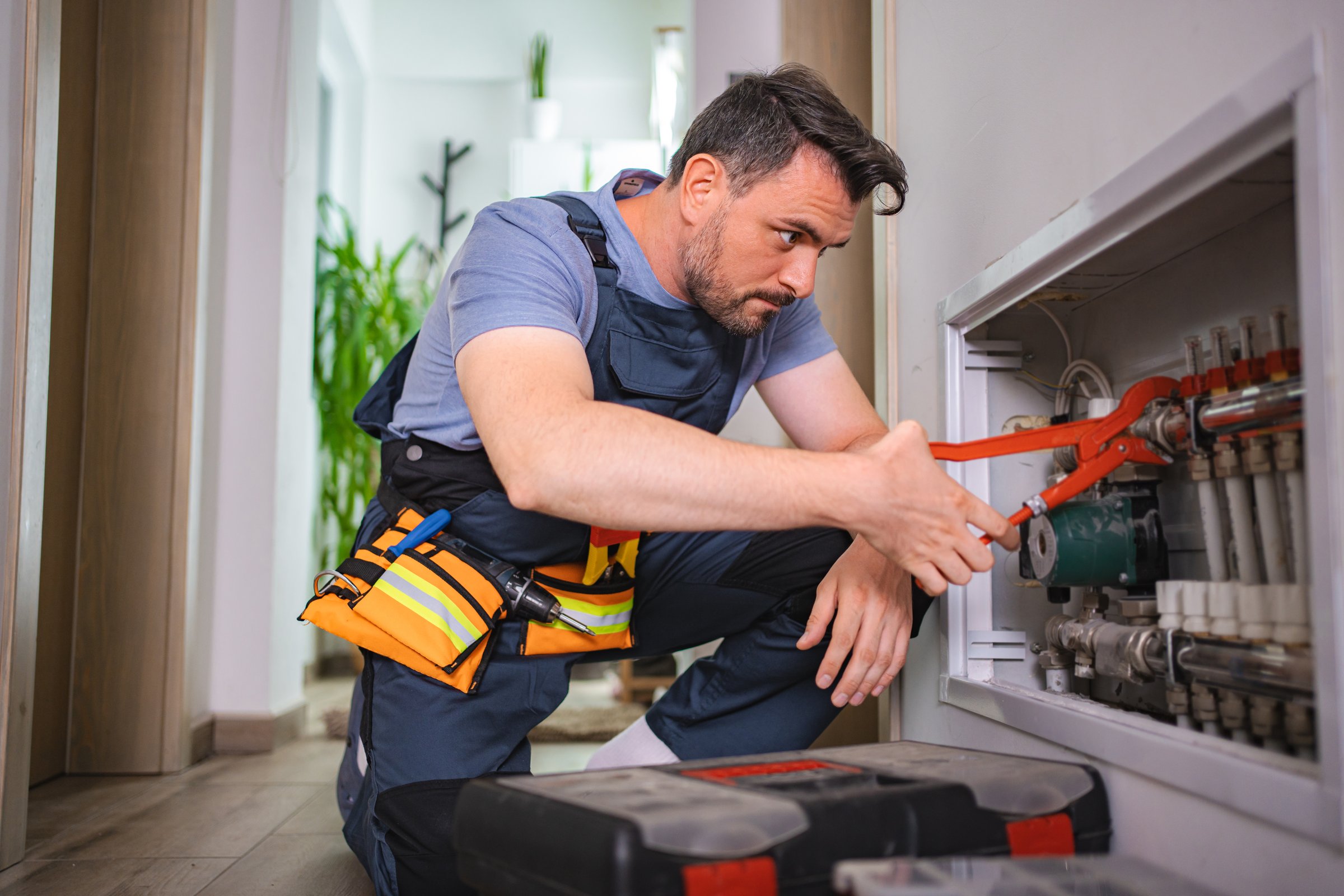 Technician repairing domestic heating system using adjustable pliers
