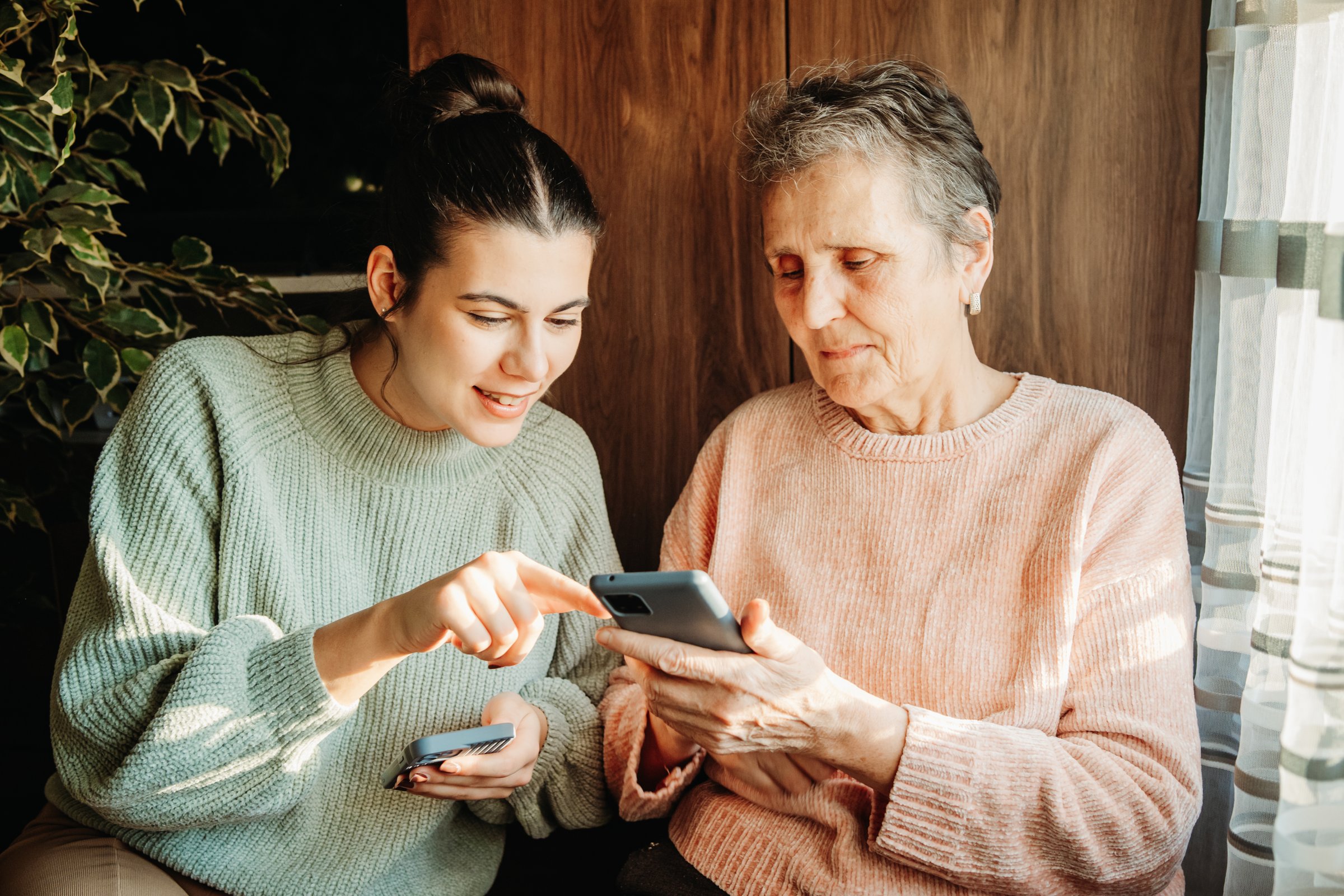Senior woman and her granddaughter using cellphone to send text messages
