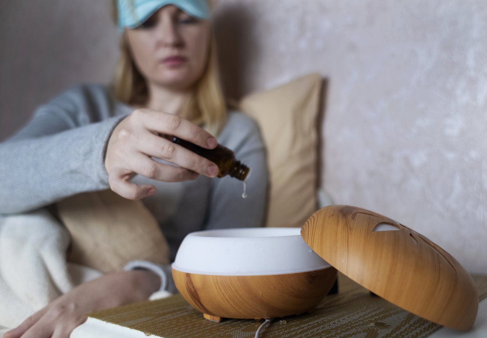 A woman drops essential oils into a humidifier for a restful sleep. Fighting sleep disorders. Relaxing effect of aromatherapy for anxiety and insomnia.