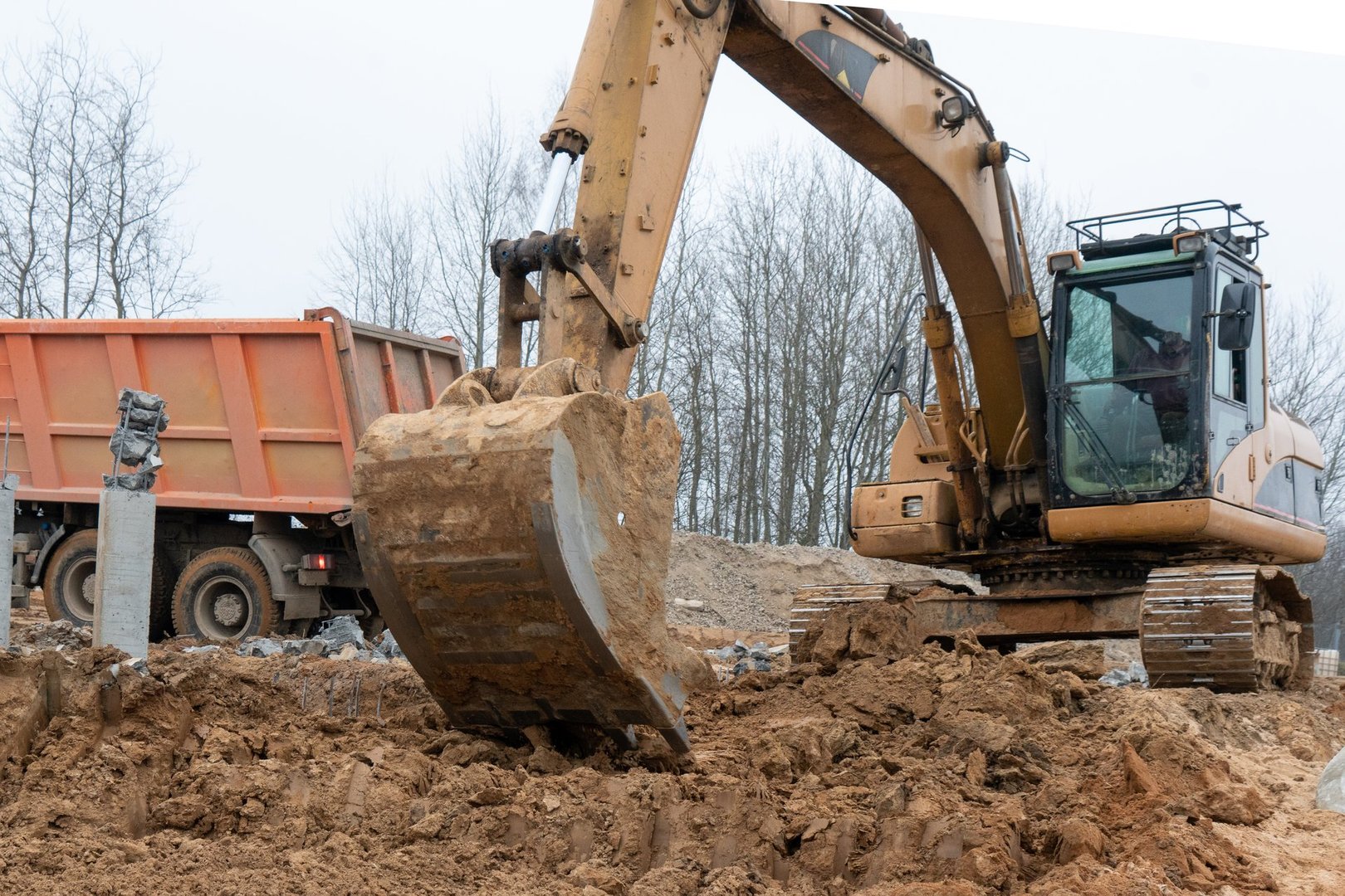Photograph of an excavator loads a truck with construction sand. High quality photo
