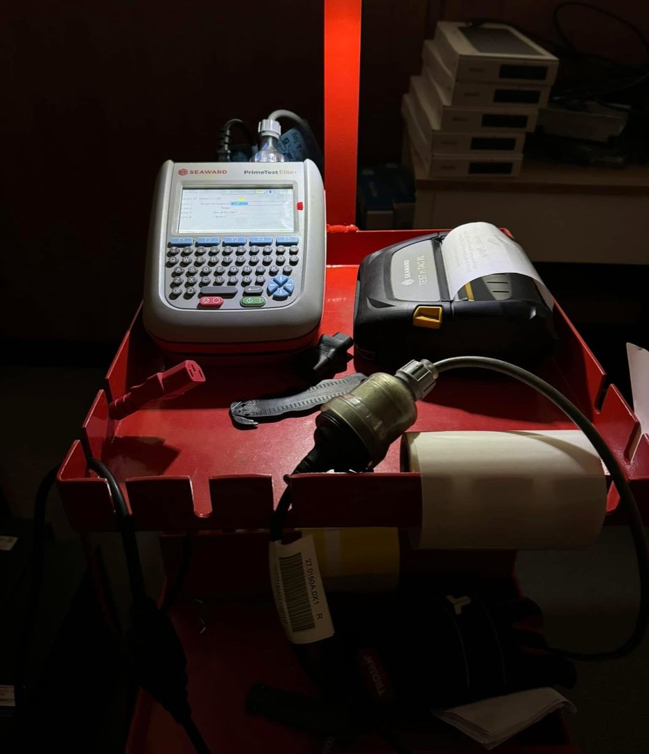 Technician conducting electrical equipment testing in a workplace environment.
