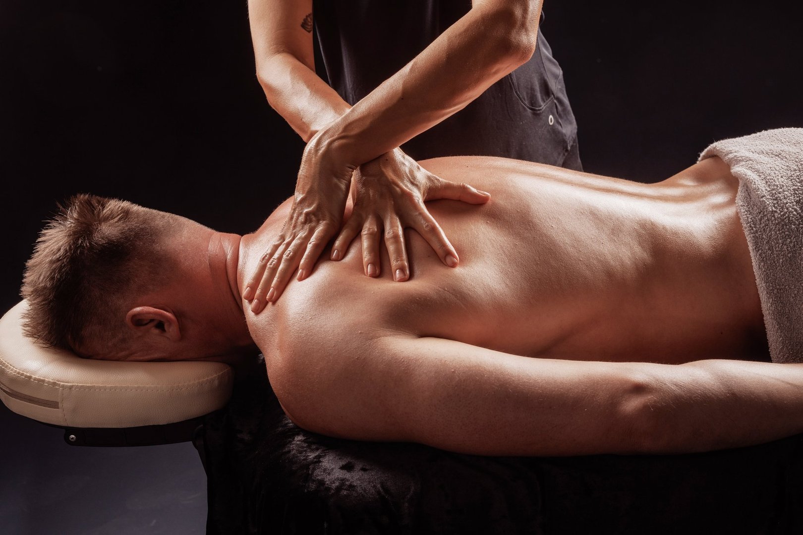 Close-up of professional deep tissue back massage on male client in wellness spa, hands applying firm pressure.