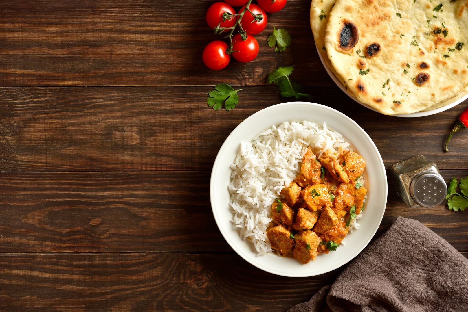 Butter chicken with basmati rice on plate on wooden background with free space. Traditional indian dish chicken tikka masala. Top view, flat lay.