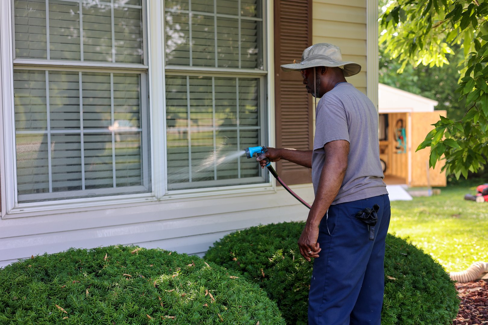 A portrait of a black man cleaning windows outside of the house