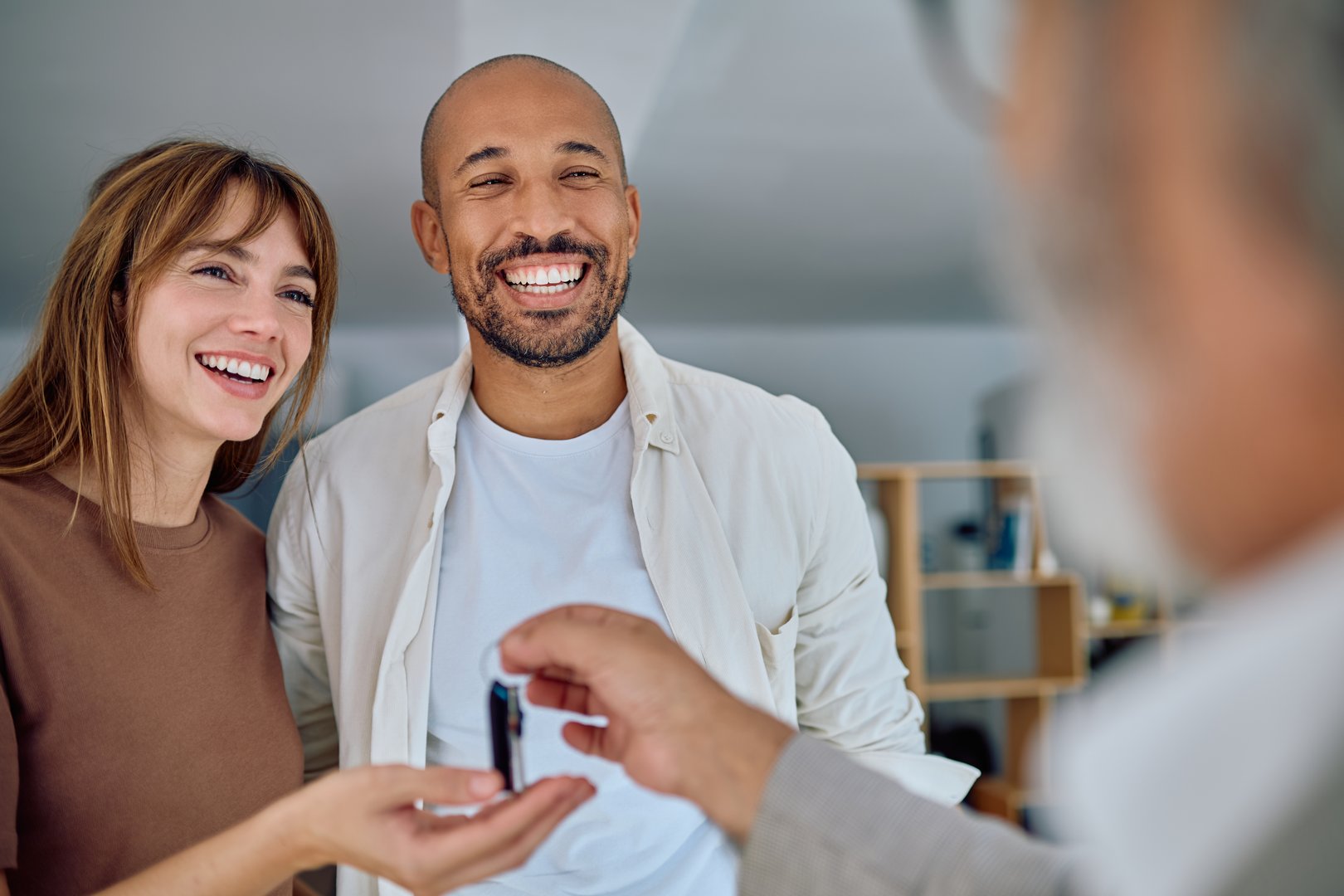 real estate agent handing over house keys to joyful homeowners