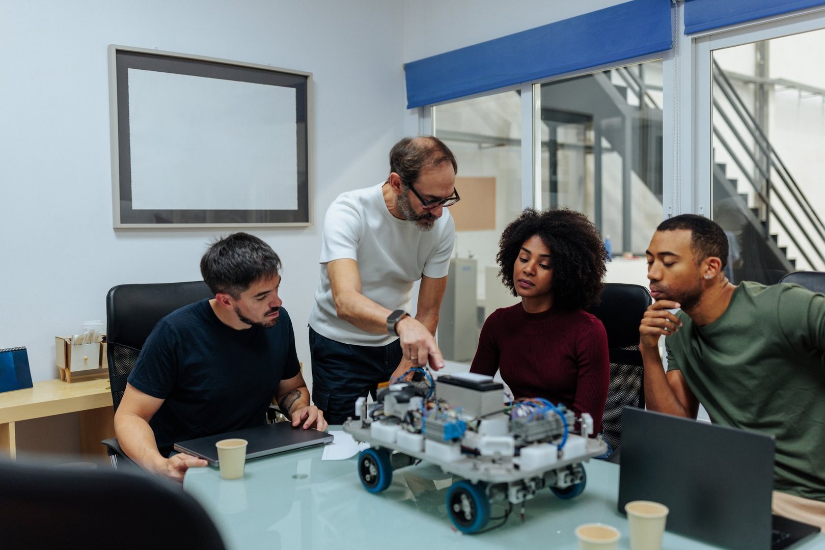 Robotics engineers team examining a prototype of a robot during a meeting in a modern office