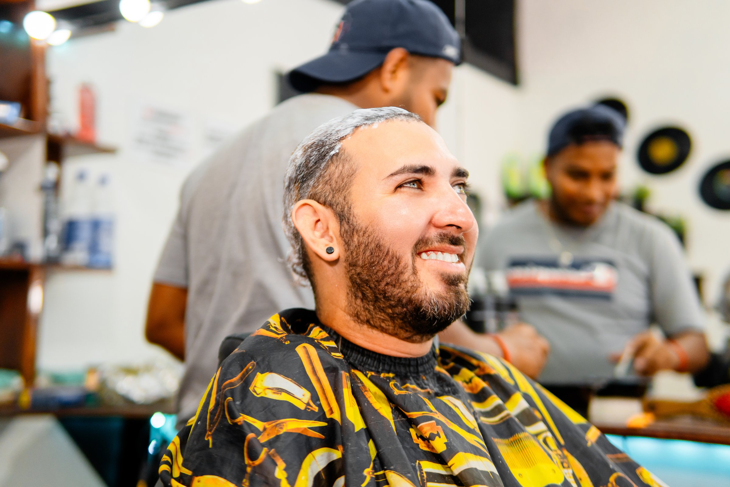 Young hispanic entrepreneur getting his hair washed at a barbershop, smiling and looking to the side