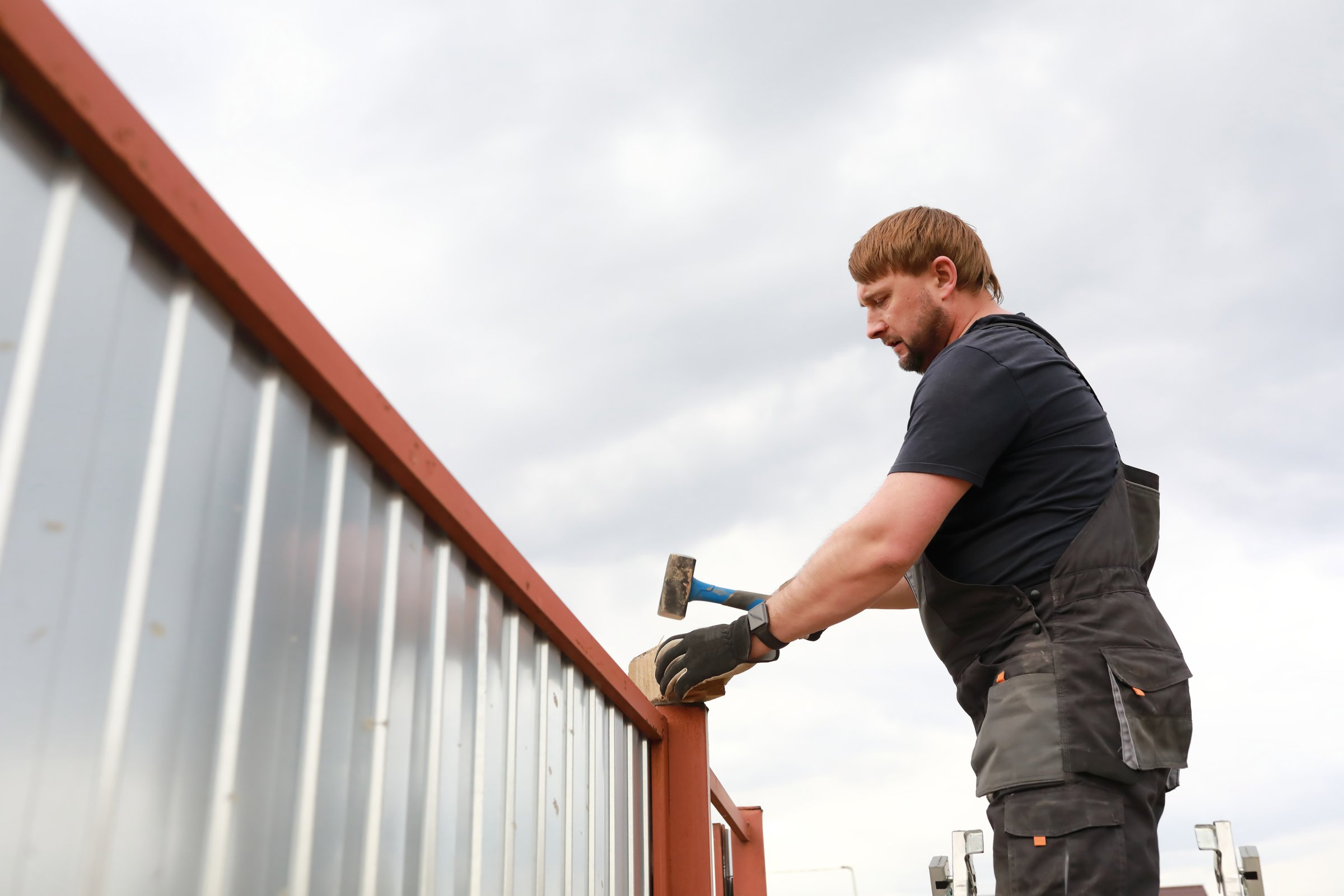 Person repairing fence near house in summer