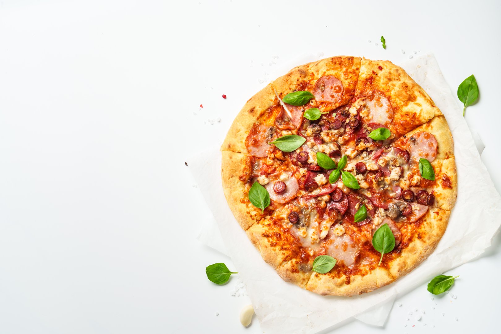 Italian pizza with ham, salami and sausages. Top view on white with space for text.