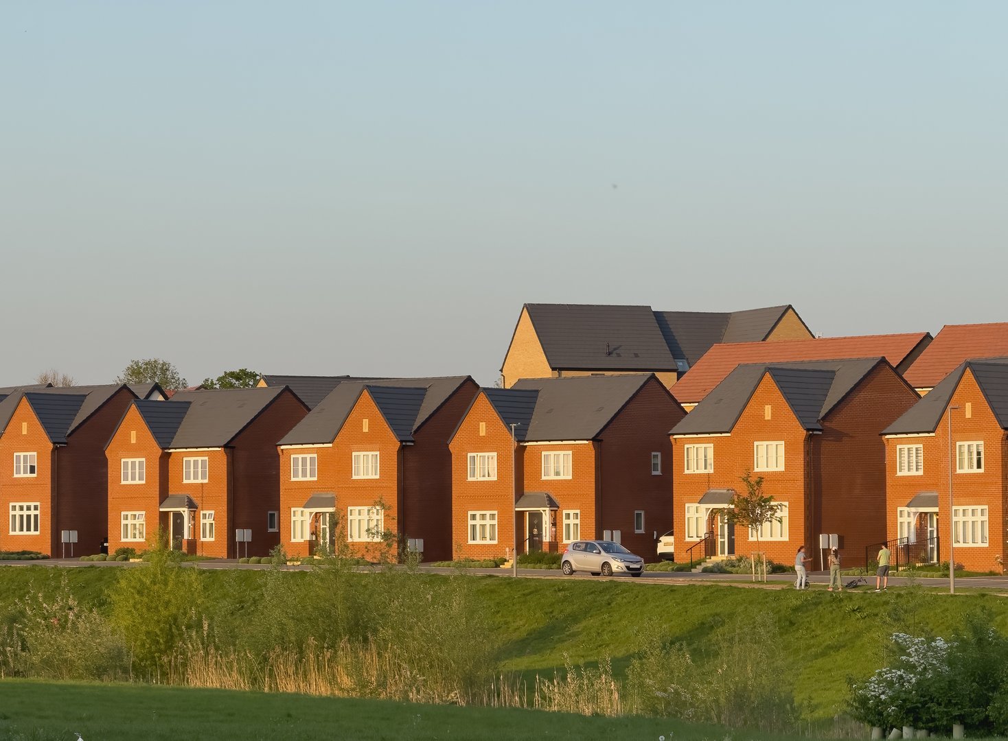 Row of Brick Homes in a Suburban Setting – Whitehouse, Milton Keynes, UK. A scenic view of a row of modern brick houses in the suburban neighborhood of Whitehouse, Milton Keynes, United Kingdom. This peaceful residential area showcases contemporary British housing, clean streets, and a family-friendly environment—ideal for themes of real estate, lifestyle, and urban planning.