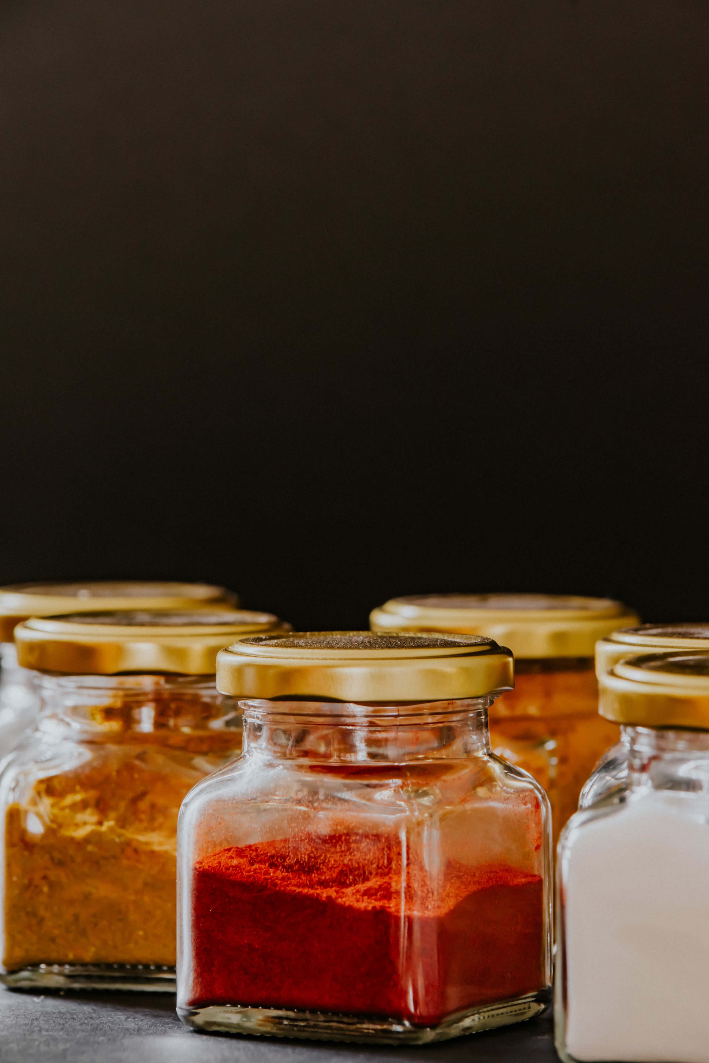 herbs and spices in can on black background.  curry, bell pepper and salt.