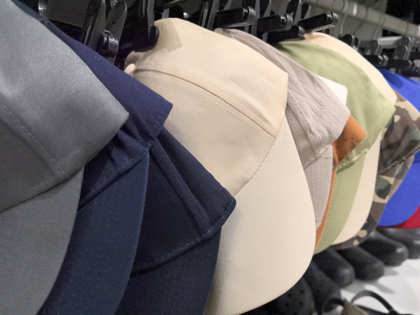 A variety of caps in different colors and styles are carefully arranged on a rack in a retail store. Shoppers can browse through these trendy accessories, perfect for any occasion.
