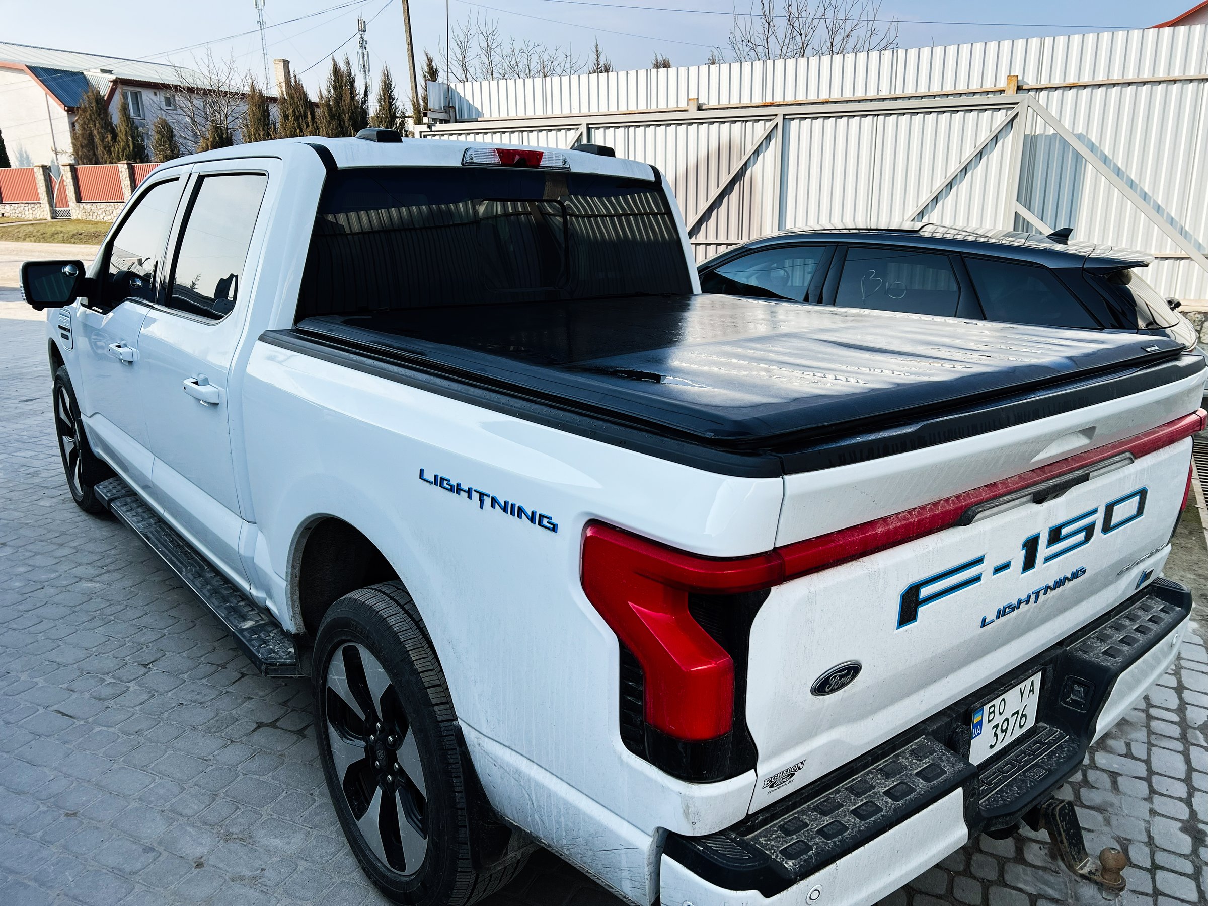 Kyiv, Ukraine - April 08, 2025: White Ford F-150 Lightning pickup truck stationary in a paved area under sunlight with visible nearby buildings.