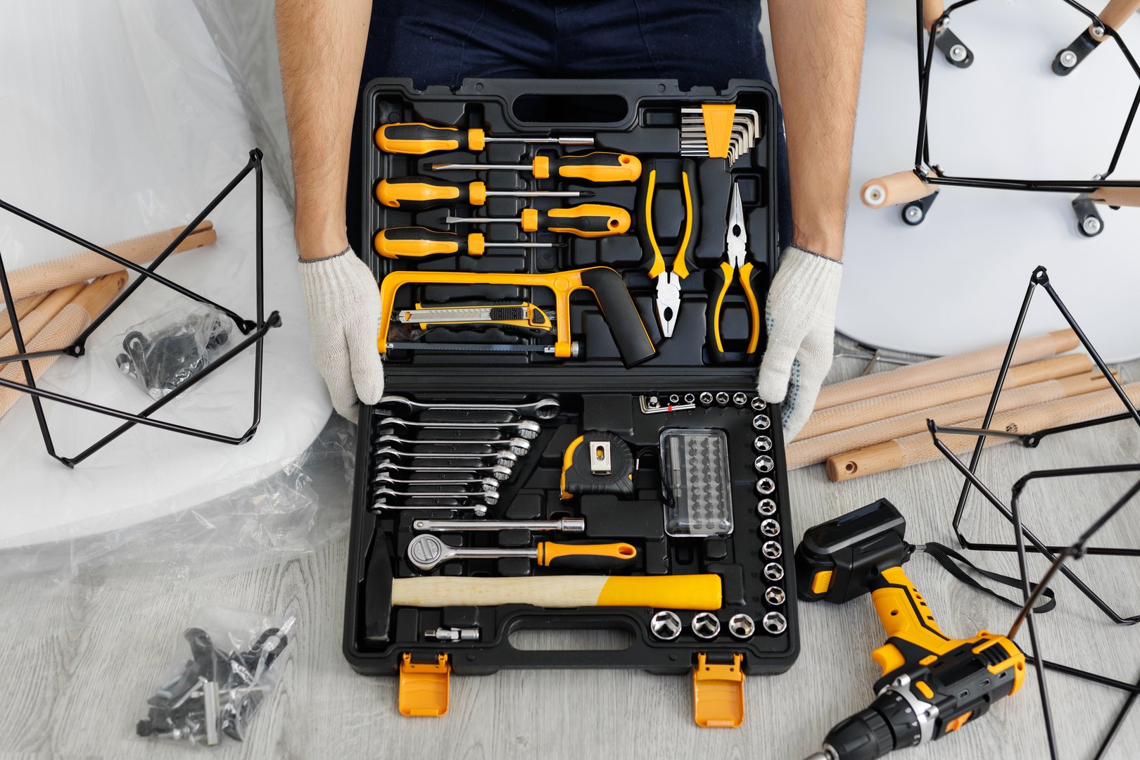 A male craftsman holds a set of tools in a suitcase on the floor in close-up