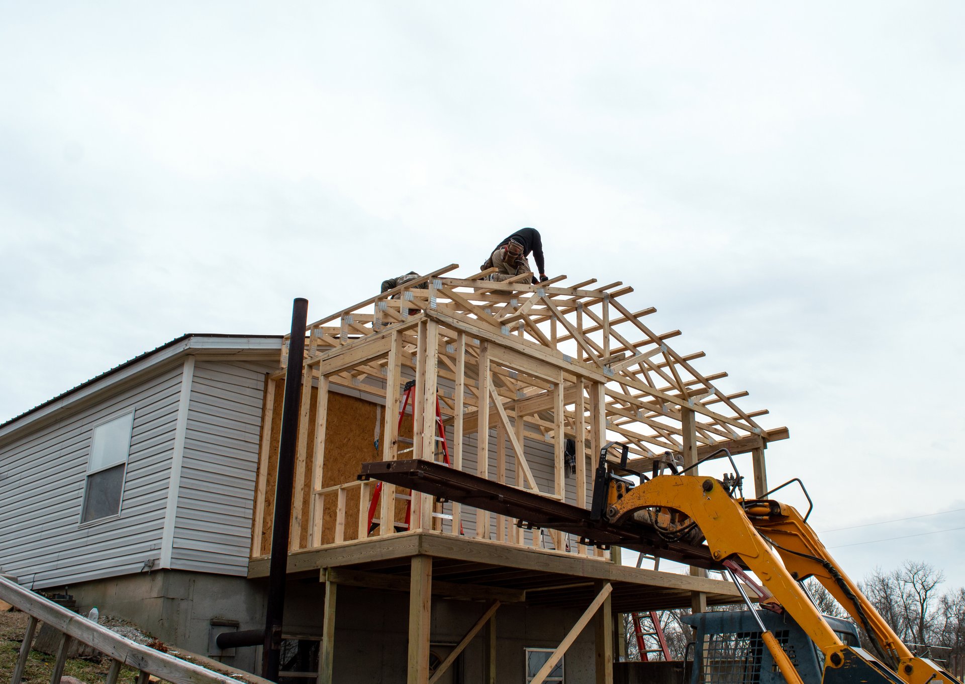 Unidentified carpenters work on the new roof, aided by some heavy equipment. Construction work is progressing nicely