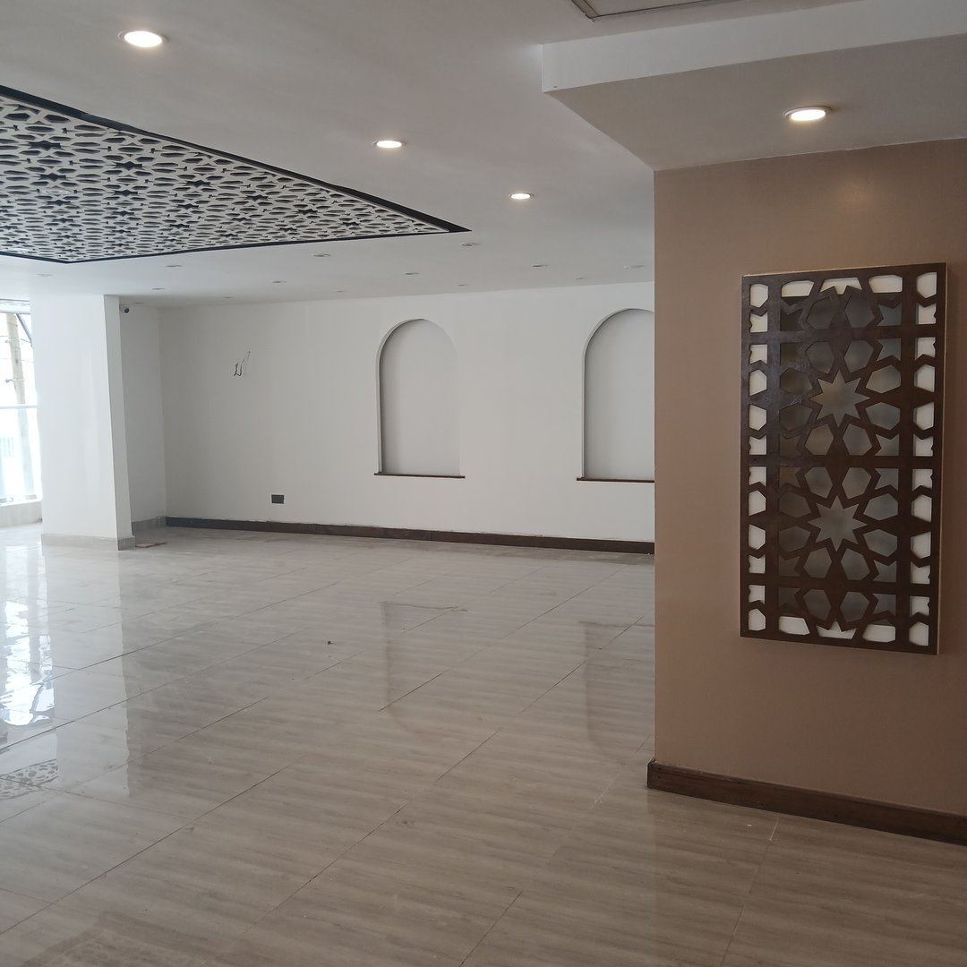 Modern, empty room with white walls, decorative panels, and recessed lighting. Floor is polished and reflective.