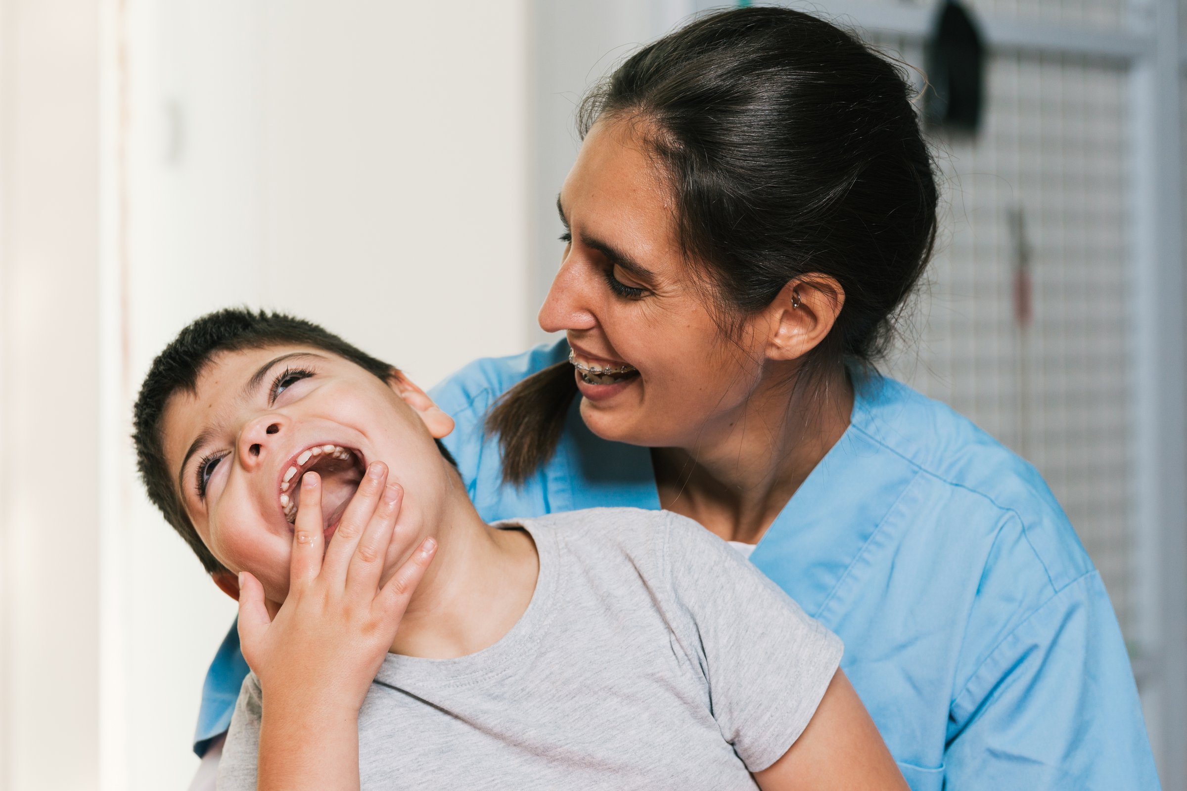 Physiotherapist and child with cerebral palsy laughing together during a rehabilitation session