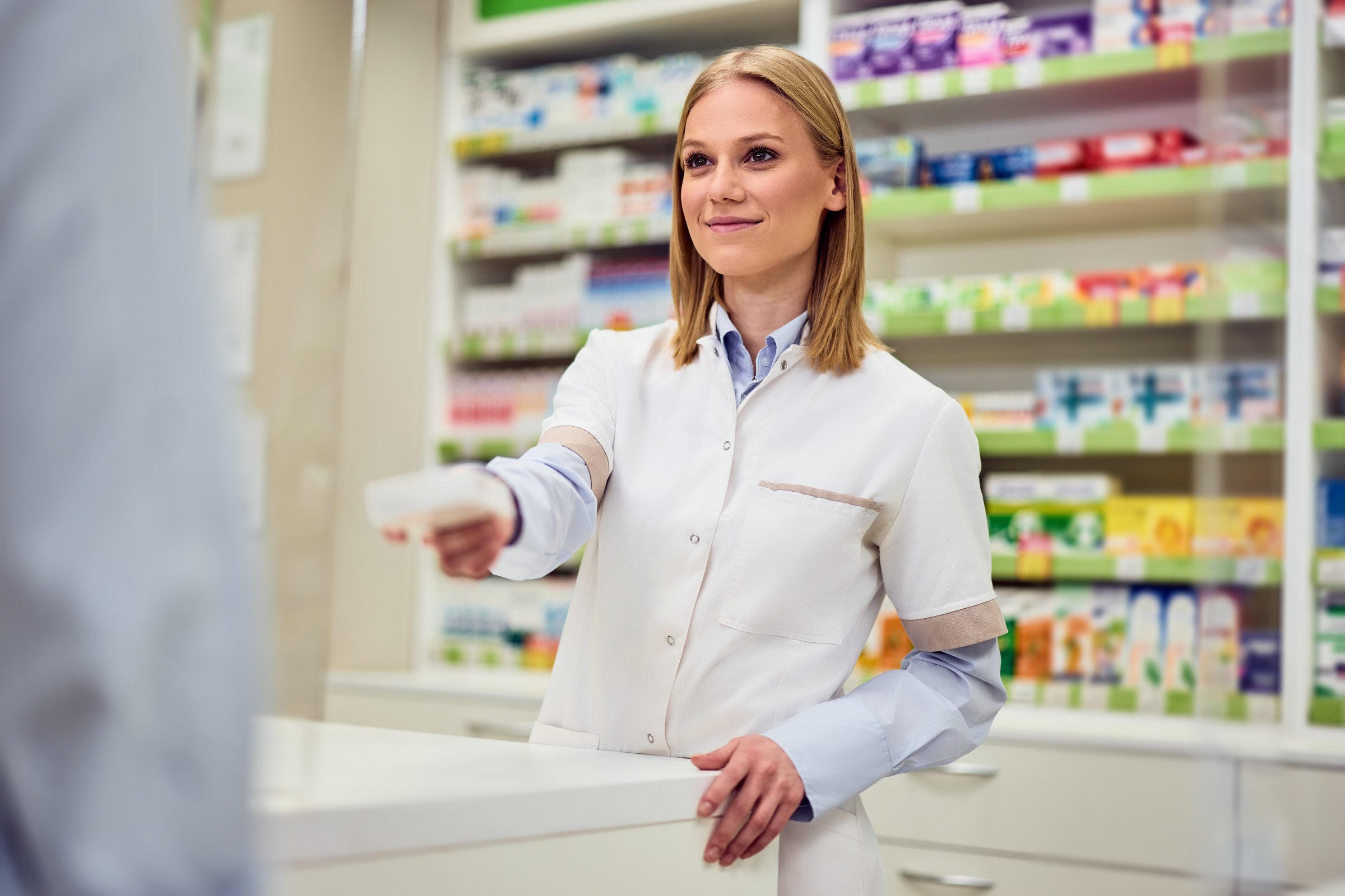 Professional pharmacist providing customer assistance in a modern pharmacy setting.