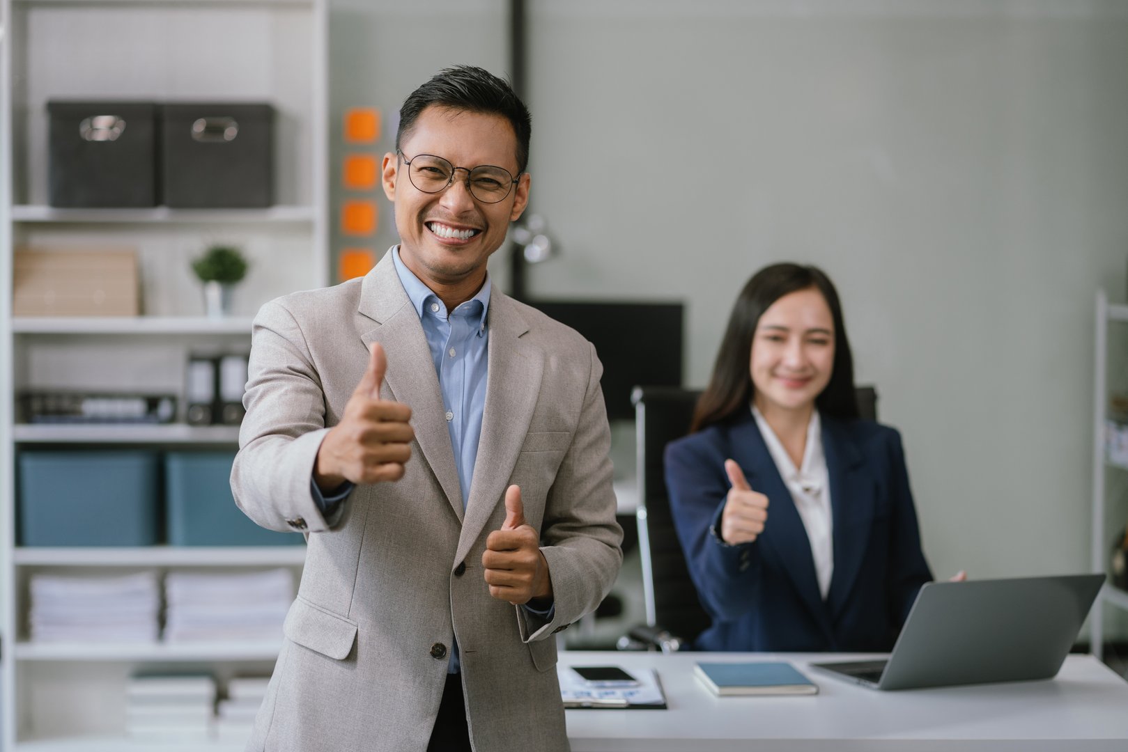 Successful young male businessman giving victory thumbs up to show success and motivation.
