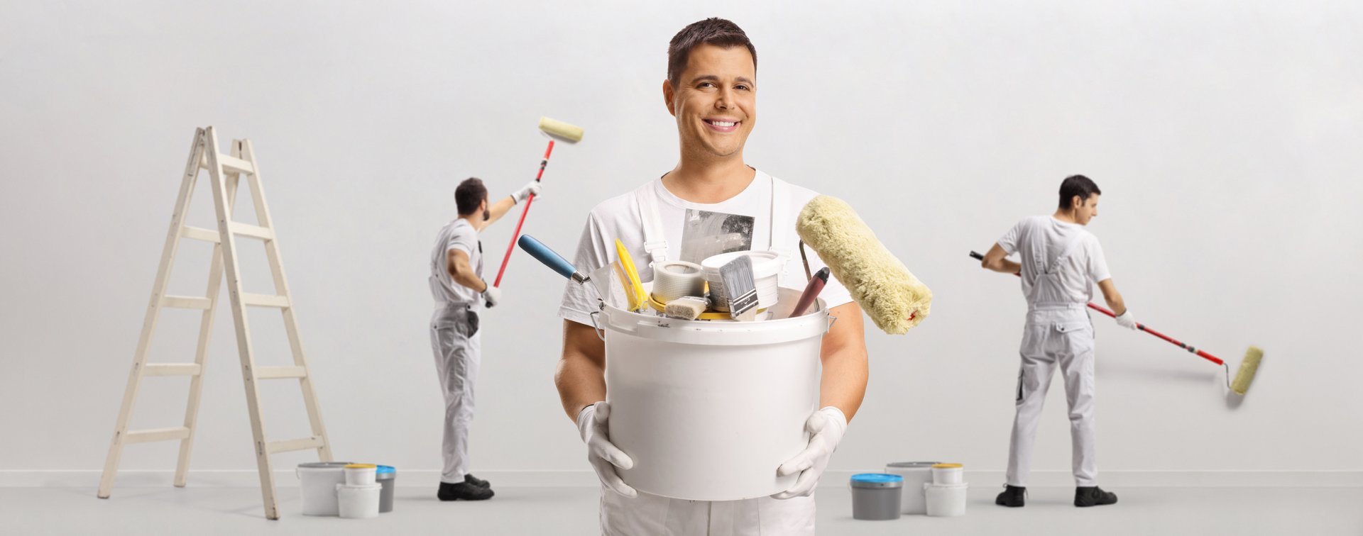 Team of painters with a bucket of tools and brushes painting a wall