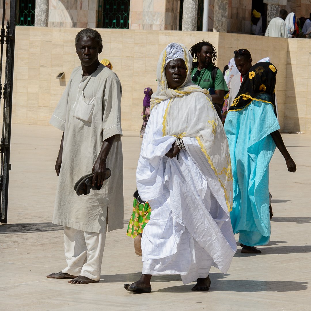 TOUBA, SENEGAL - APR 26, 2017: Unidentified Senegalese people in colored traditional clothes walk in the Great Mosque of Touba, the home of the Mouride Brotherhood