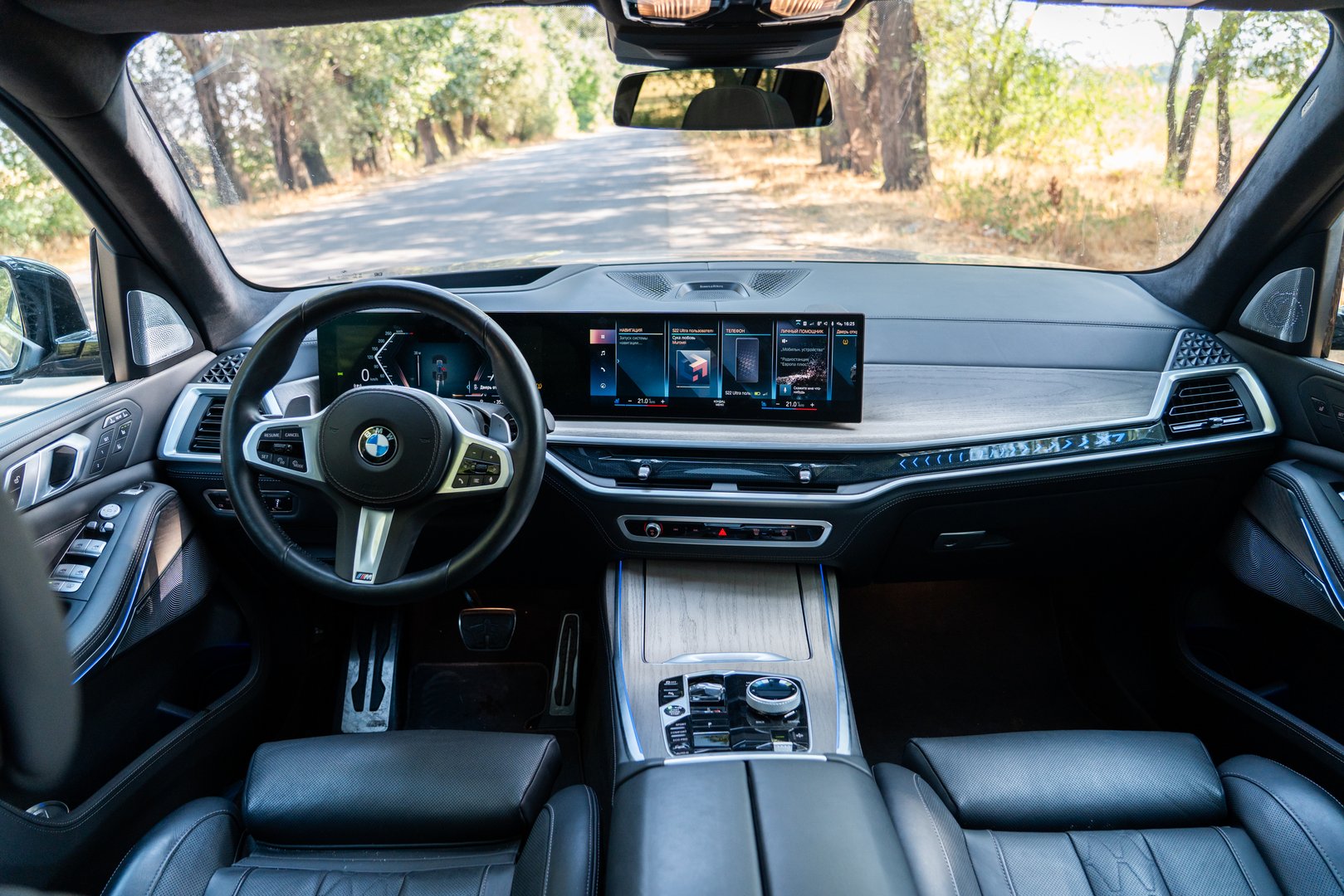 Bishkek, Kyrgyzstan - October 12, 2024: The detailed interior of a 2024 BMW X7, showcasing the driver's perspective with the steering wheel, dual digital displays, and center console, overlooking a road
