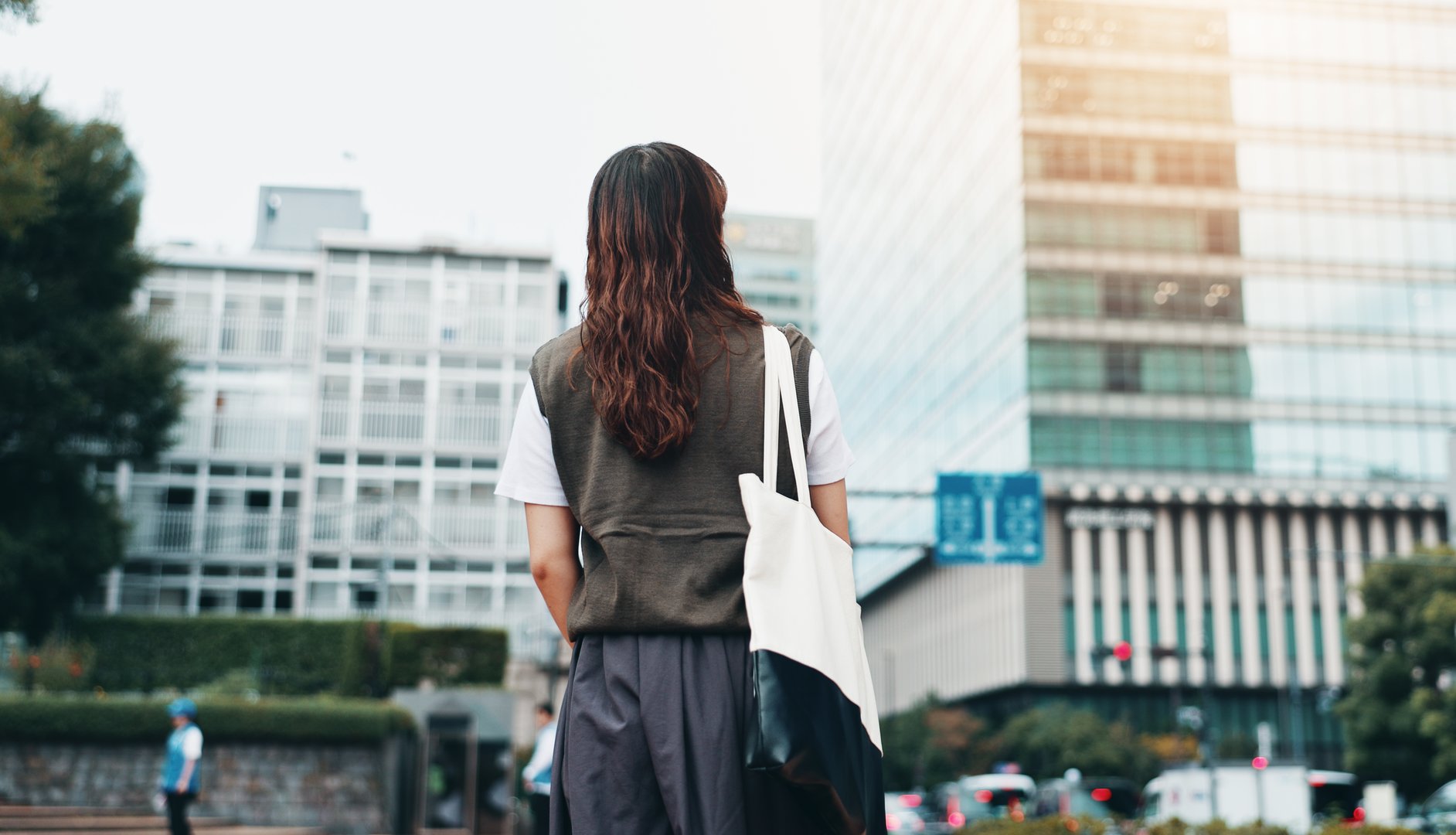 Walking, bag and back of woman in city for travel with international exchange student program. Learn, education and young female person on commuting journey in town for university or college in Japan