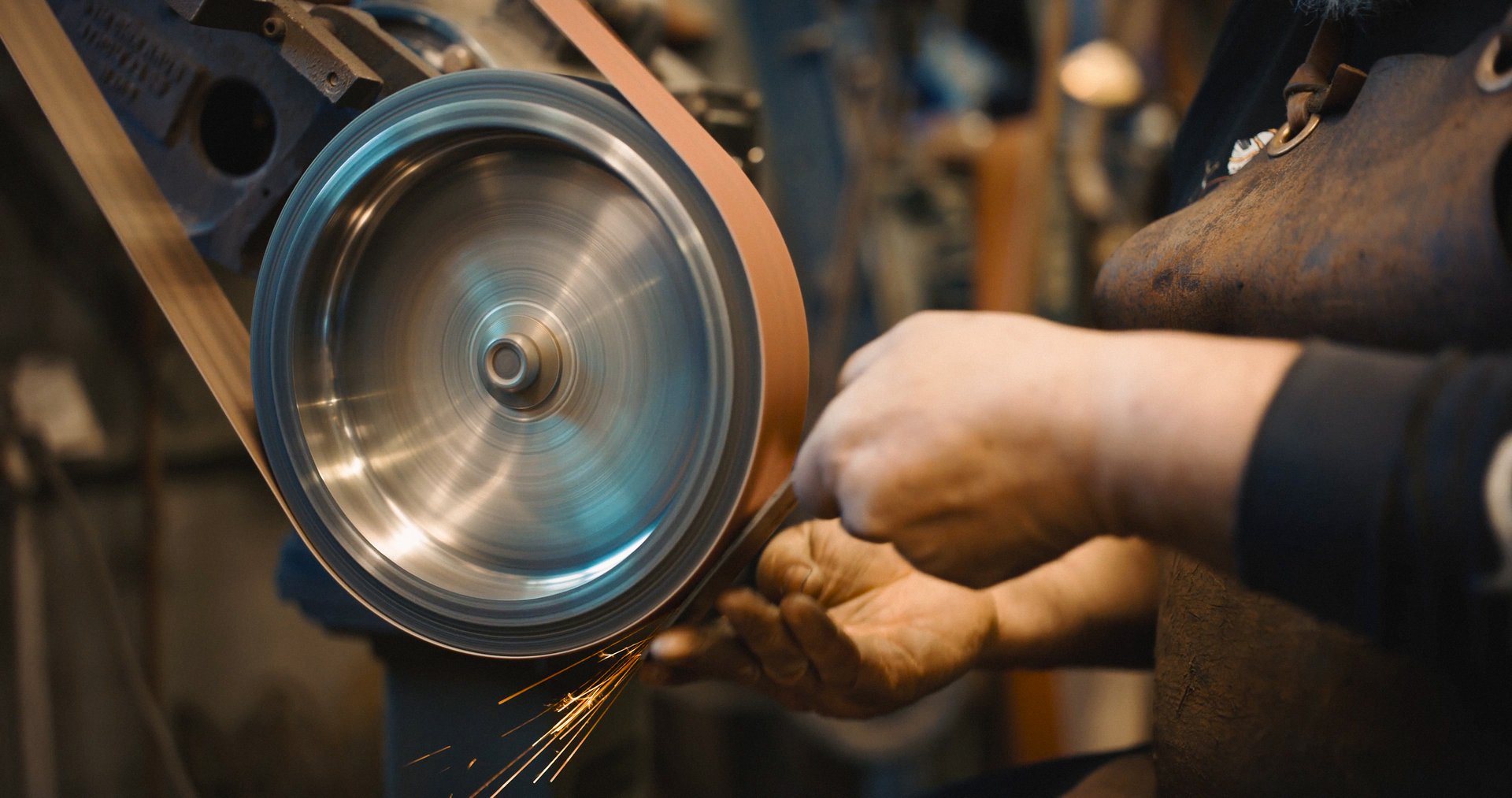Craftsman uses a belt sander in a mechanical workshop.