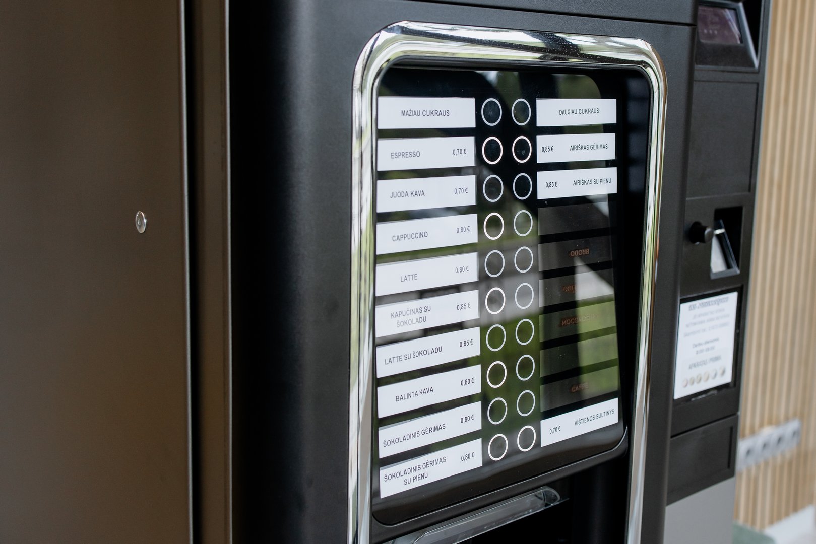 Close-up view of a modern coffee vending machine with a digital selection panel offering various hot drinks in a public space