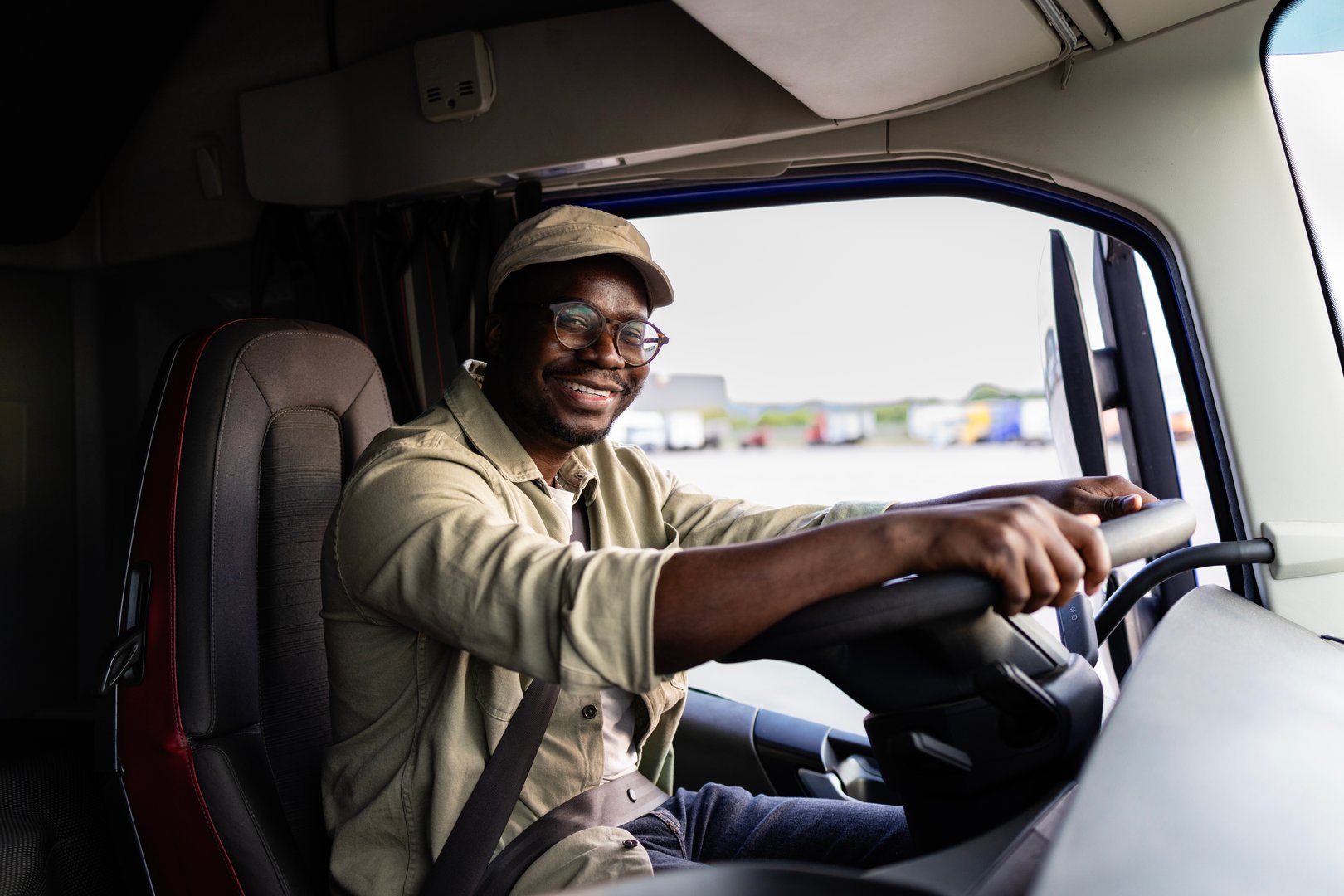 Professional driver sitting in the cabin and driving truck.