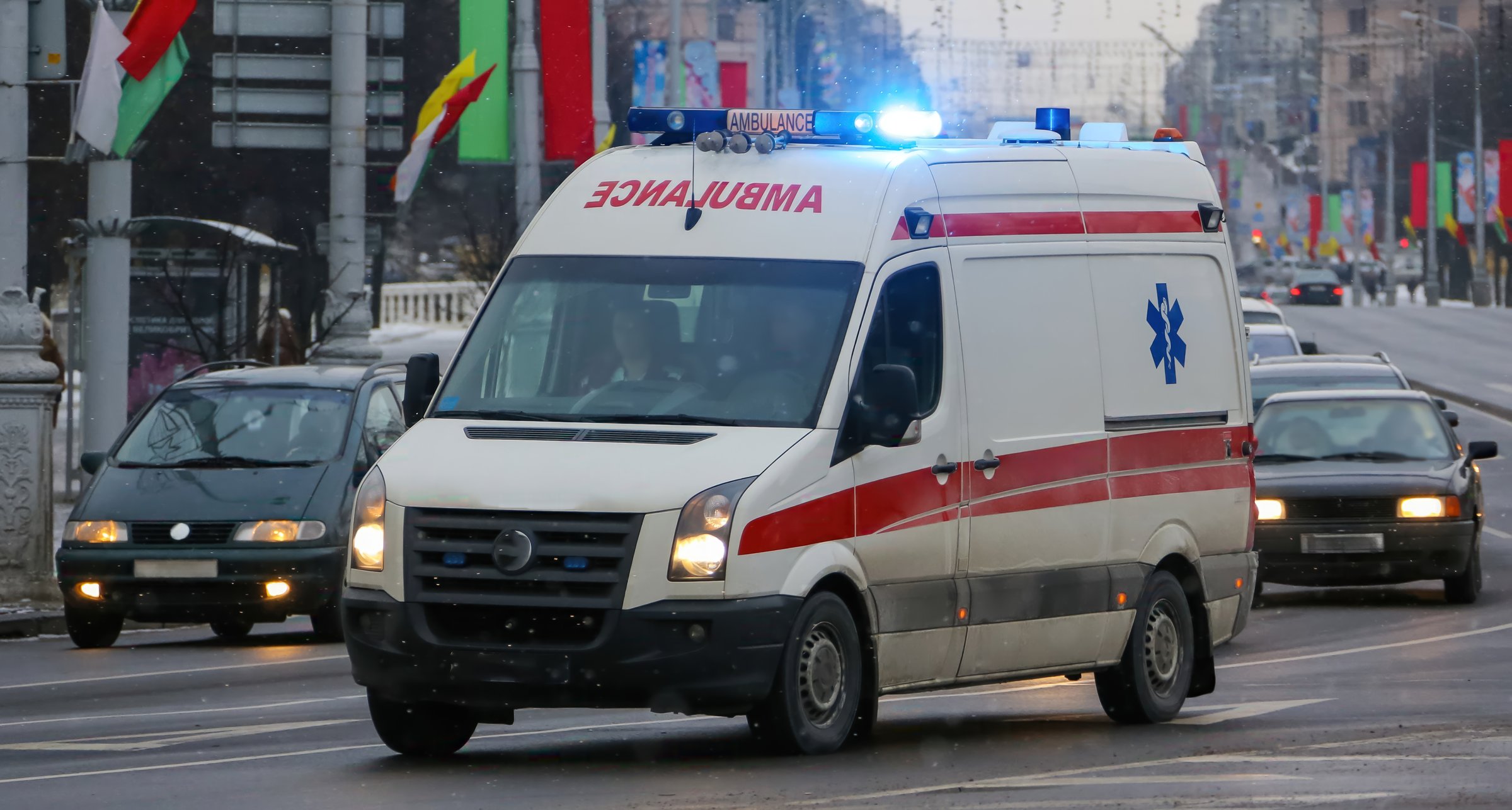 An ambulance rushes through a crowded street with traffic