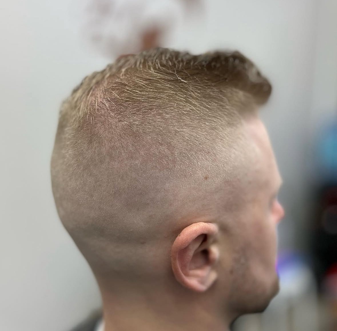 Side profile of a man with a fade haircut, featuring short buzzed sides and slightly longer hair on top.