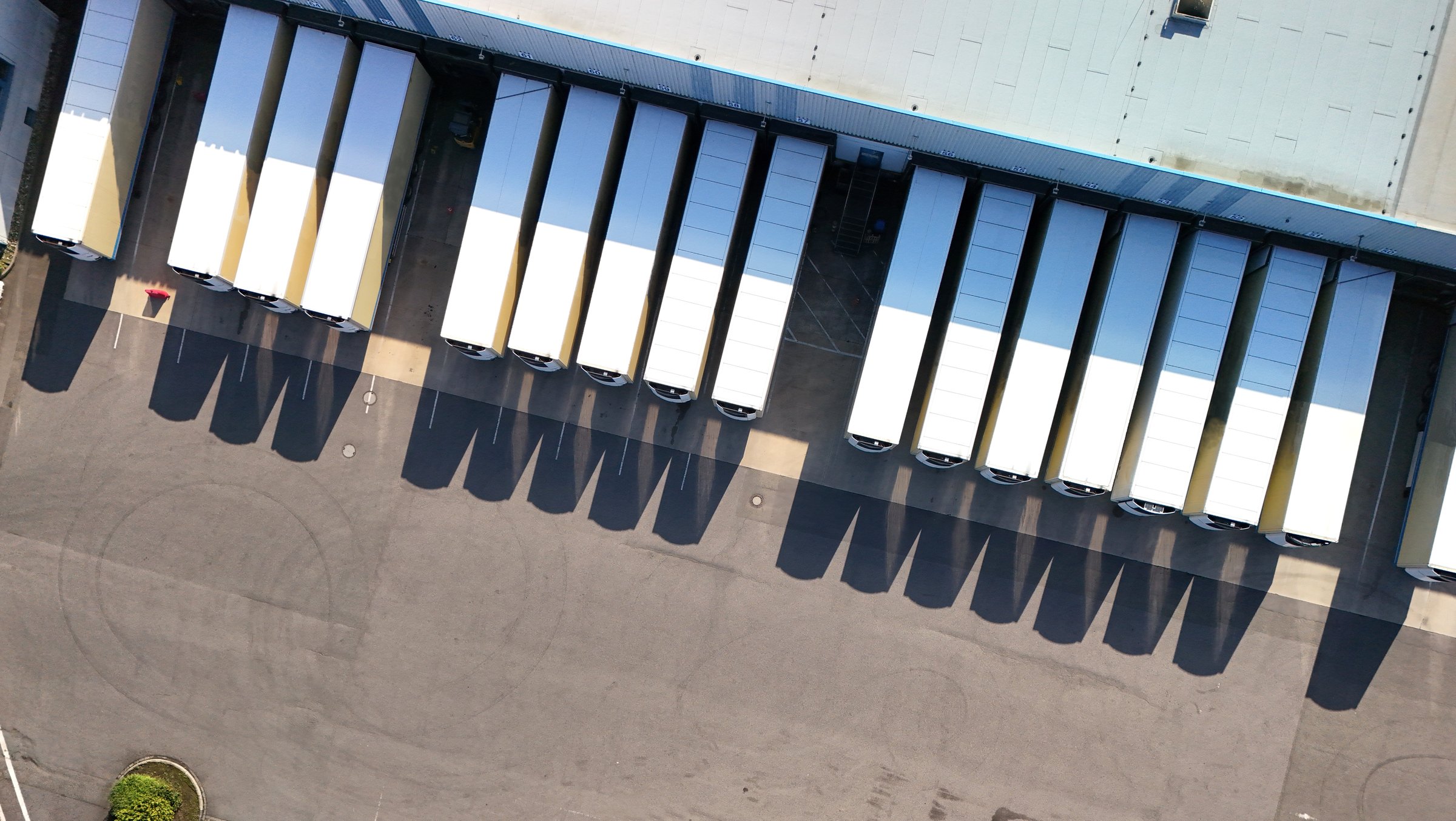 Aerial view of a logistics center with multiple parked trucks. The scene illustrates organization and infrastructure in freight transport and goods distribution. Ideal for topics related to logistics, transportation, shipping, and supply chain management.