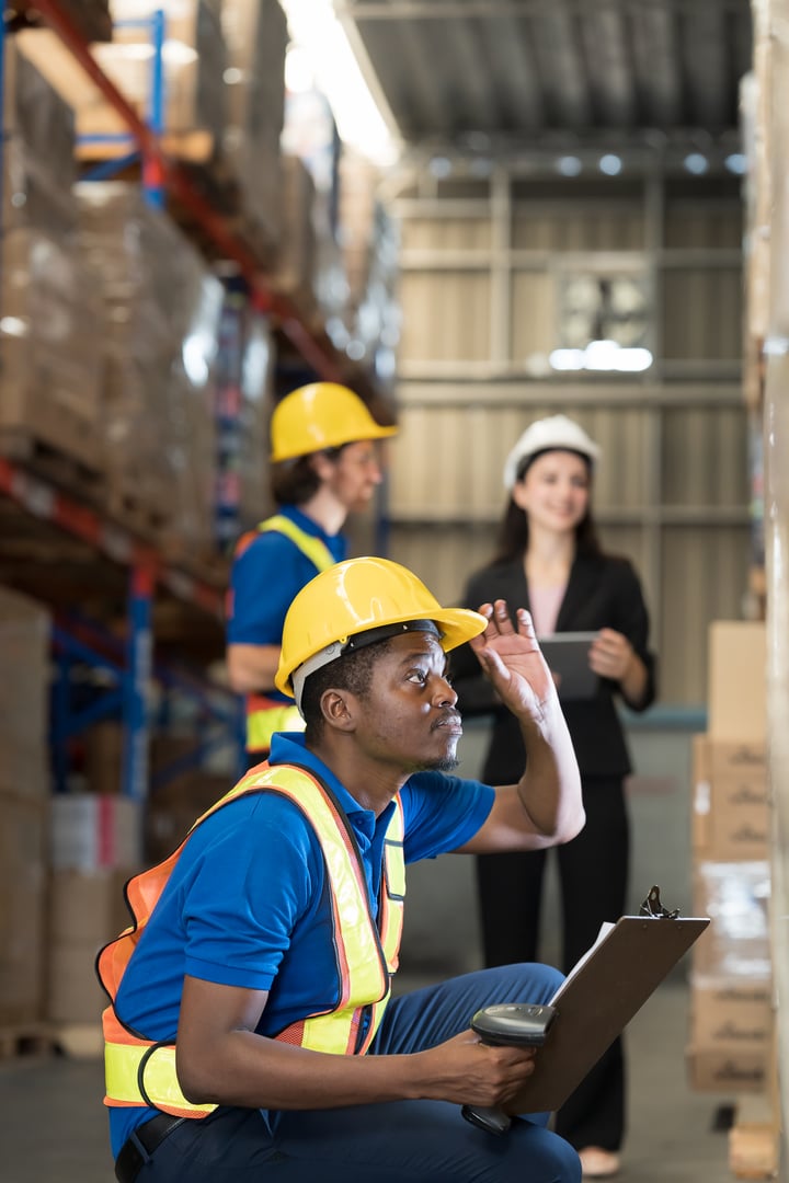 African American male warehouse worker. Male worker holding clipboard and scanning barcodes on boxes on shelf pallet. Male warehouse worker working in storage warehouse