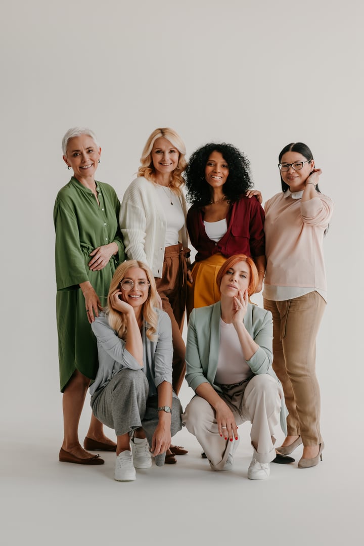 Multi-ethnic group of mature women bonding and smiling against grey background