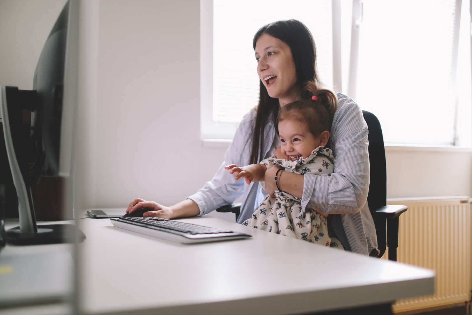 Mother working from home office with her daughter.