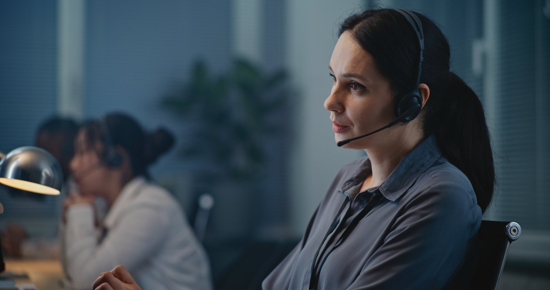 Call center office of mental health helpline: Close up of Caucasian female crisis hotline worker talking on headset, consulting person online, providing psychological help. Emotional support concept.