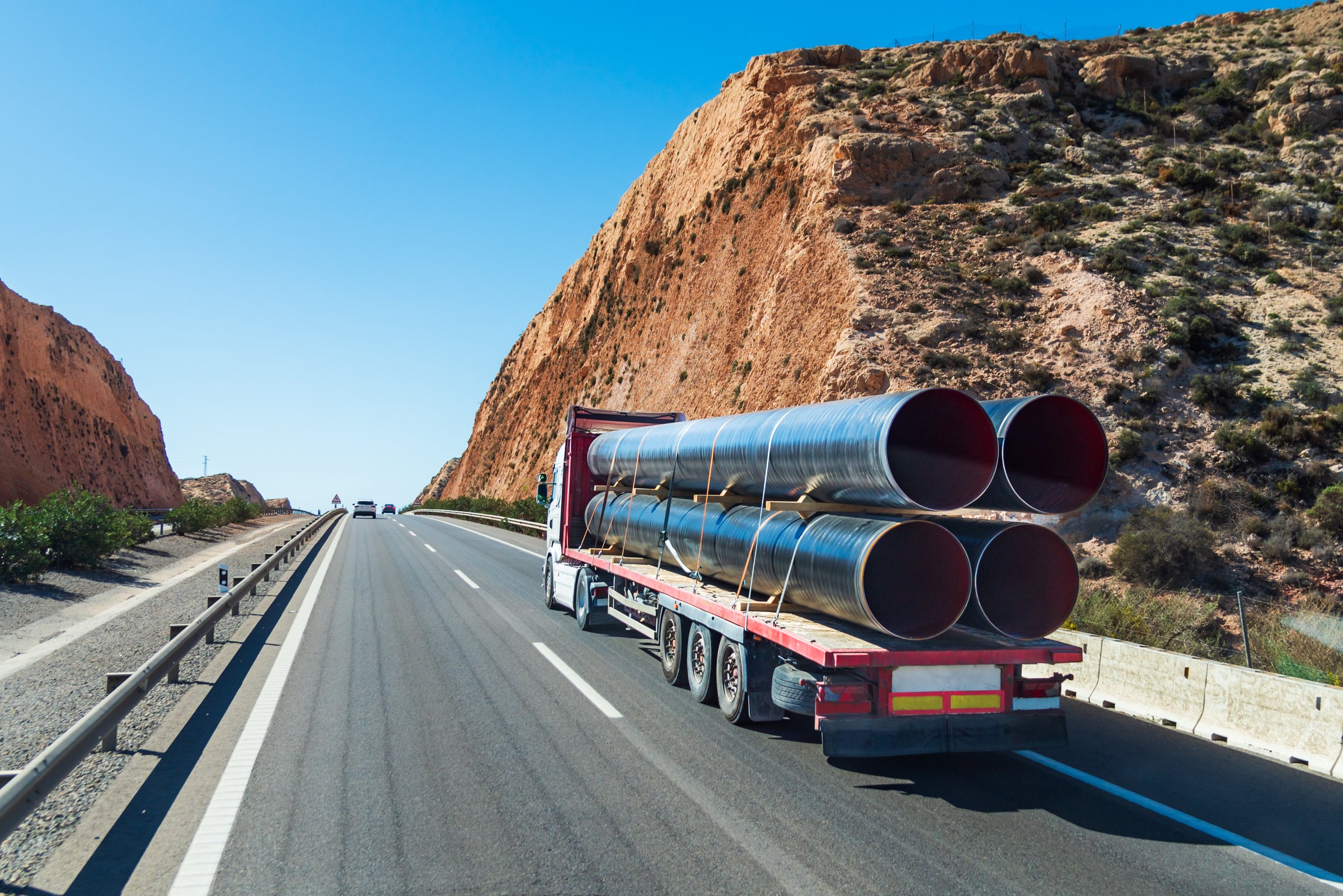 Truck transporting large pipes, used to create underwater lines for transporting gases - example of flatbed transportation