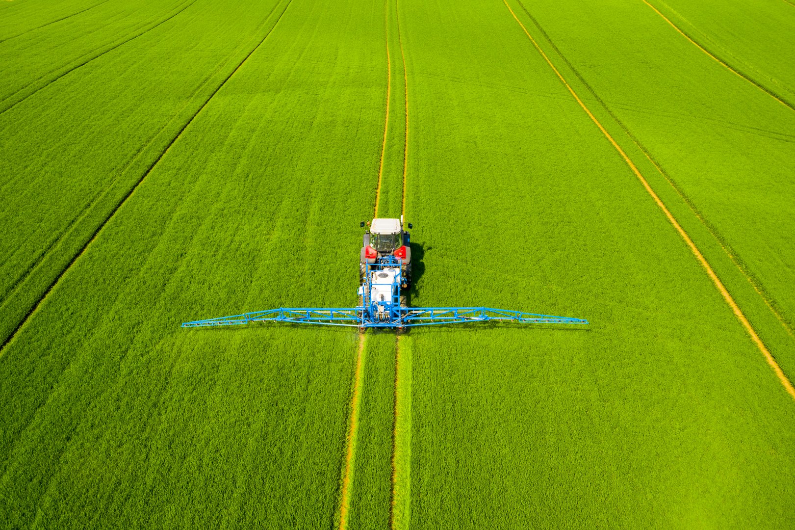 Agricultural tractor spraying crops in field