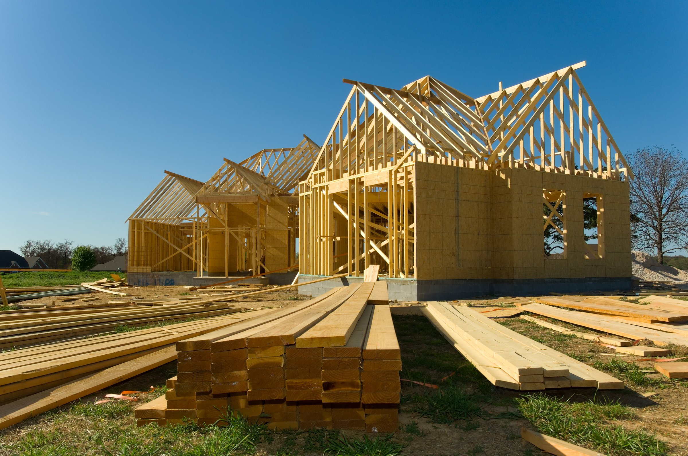 Brand new home under construction with wood, trusses against blue sky