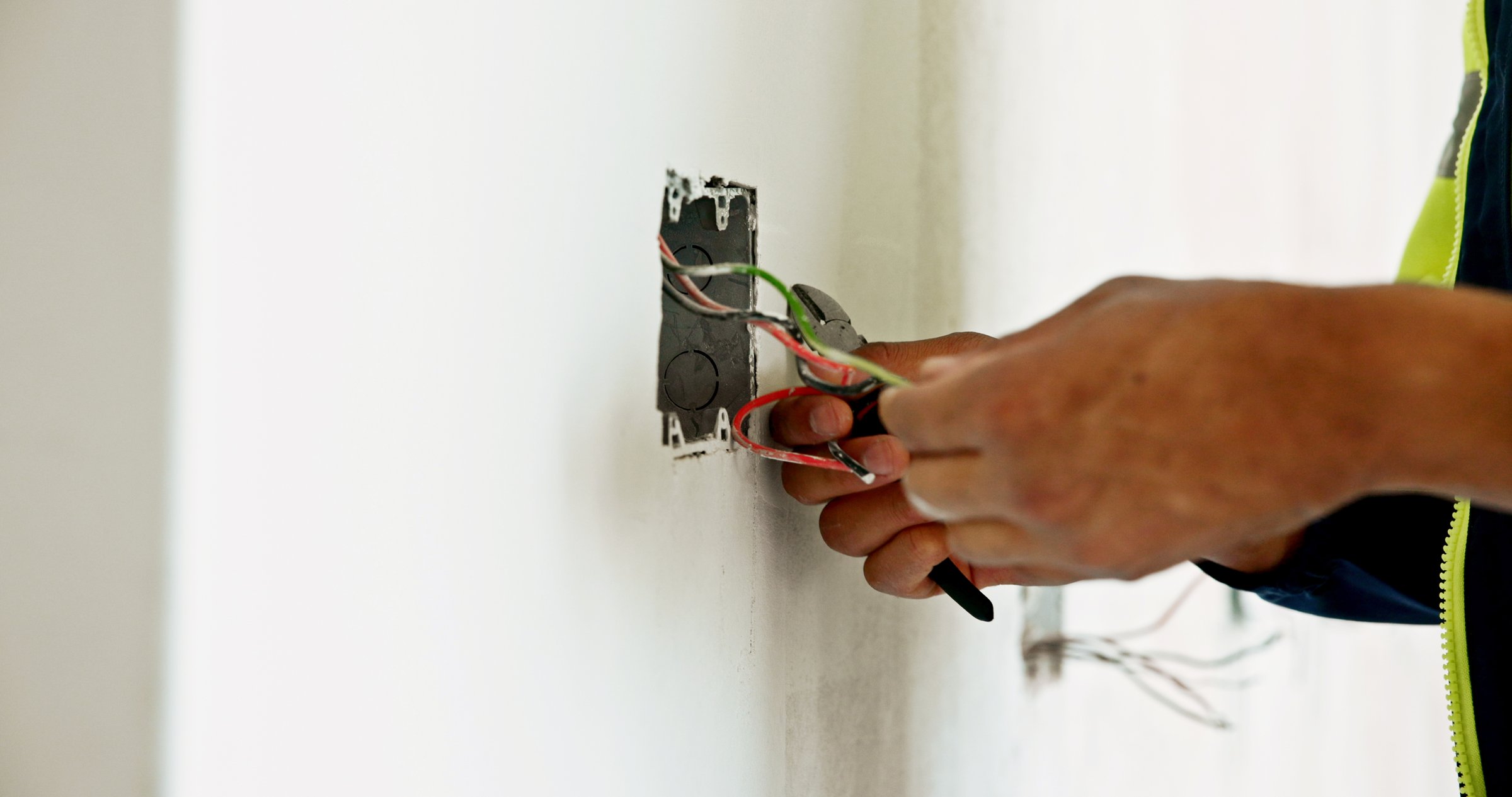 Man, hands and wires on construction site for renovation, connection or electrician with tools. Electrical engineer, switch fitting or cables in building wall for current flow, inspection or handyman