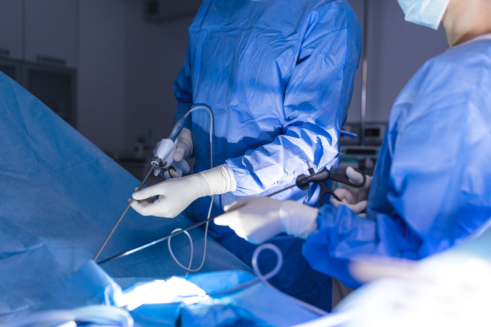 Process of gynecological surgery operation using laparoscopic equipment. Group of surgeons in operating room with surgery equipment. Background