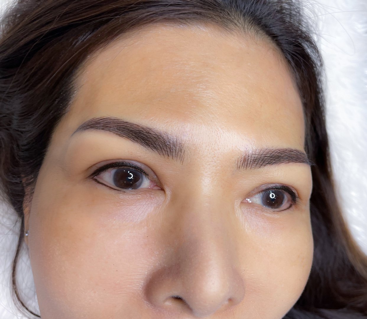 Eyebrow tattooing, upper and lower eyelid tattooing completed. Asian female customer. Close-up images show the details of the eyebrow tattooing, which are lines that look like real eyebrow hairs.