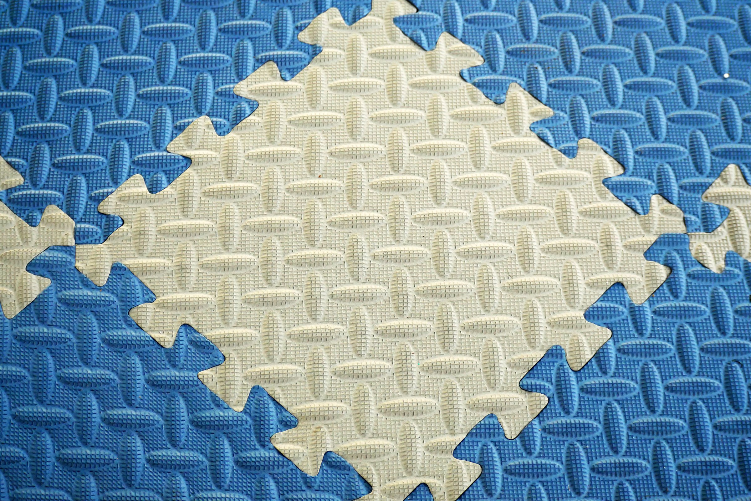 Close-up photo of interlocking blue and white puzzle mats. The mattress background is made of soft and soft foam