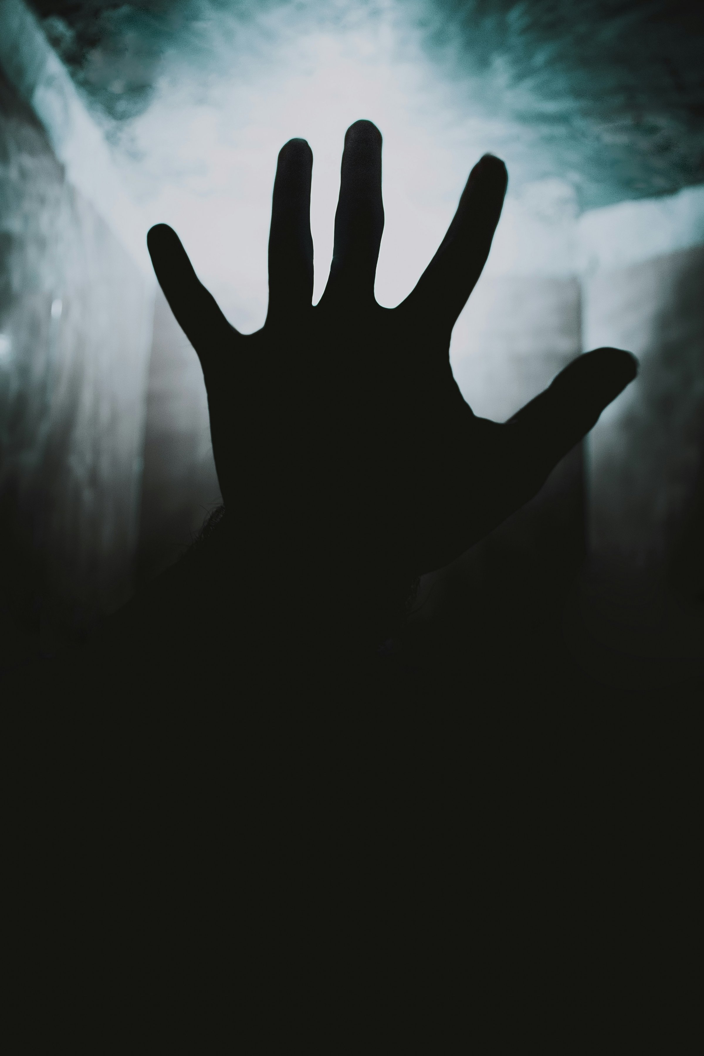 Silhouette of an outstretched hand against a bright, textured background, creating a dramatic contrast.