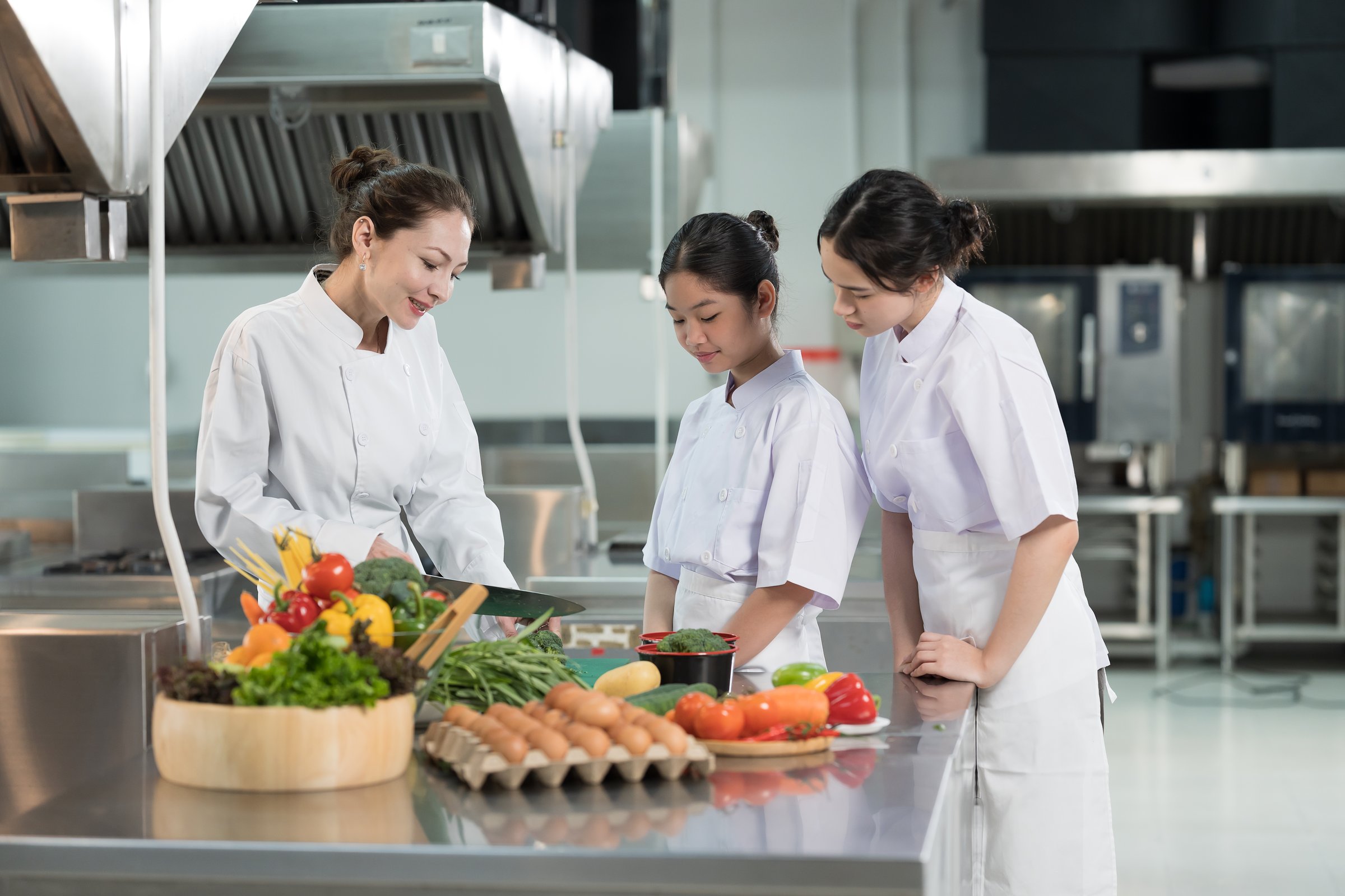 Group of young female chef wearing white apron during preparing food and learning cooking in kitchen