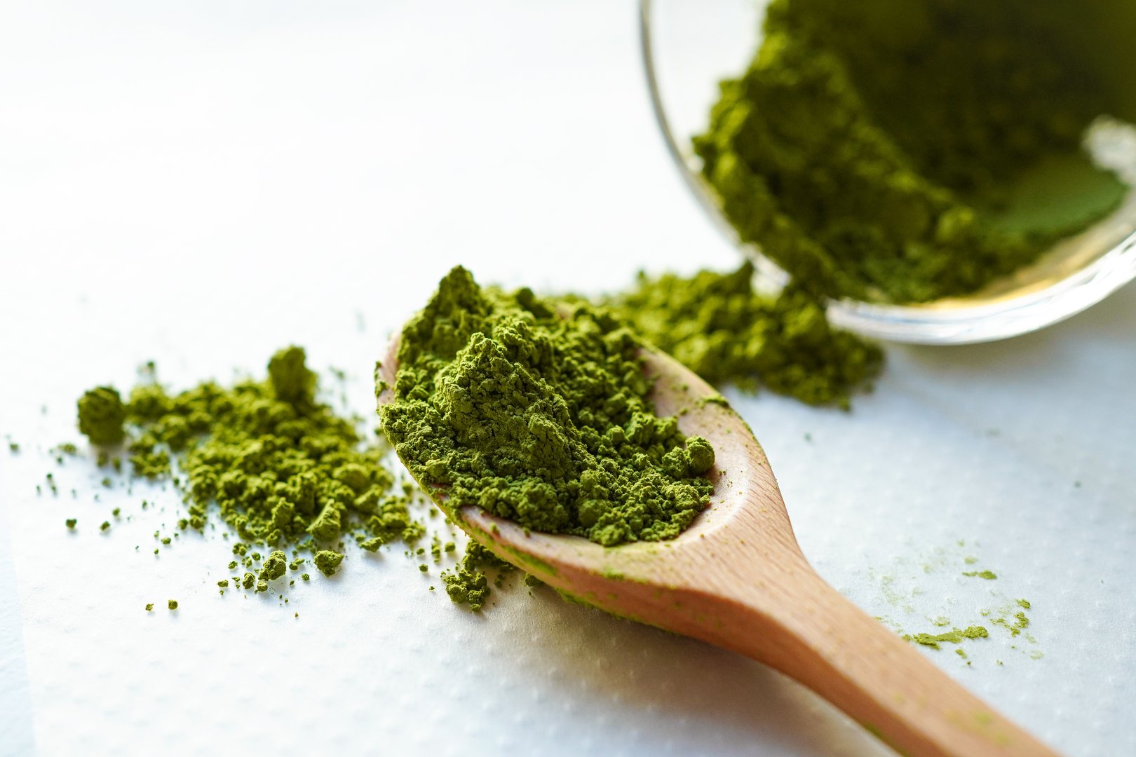 Organic matcha powder in wooden spoon with white background