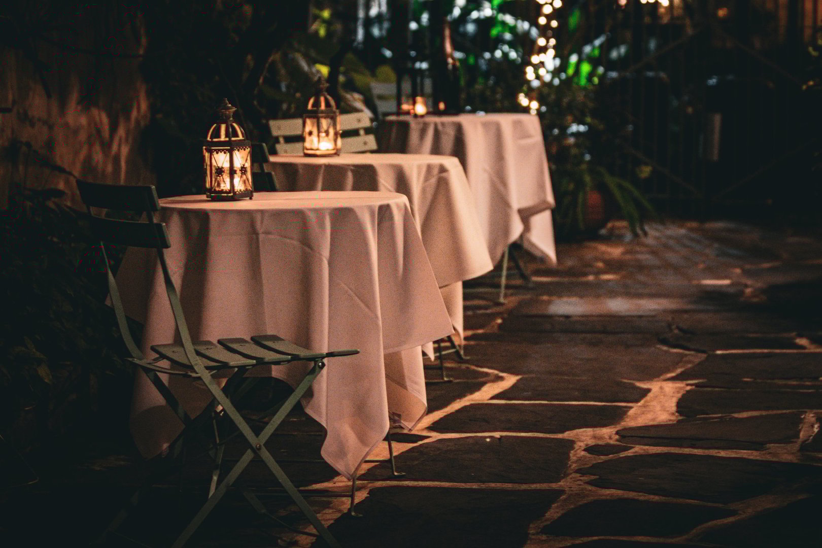 Intimate outdoor dining by candlelight on cobblestone with white table cloth in the French Quarter of New Orleans.