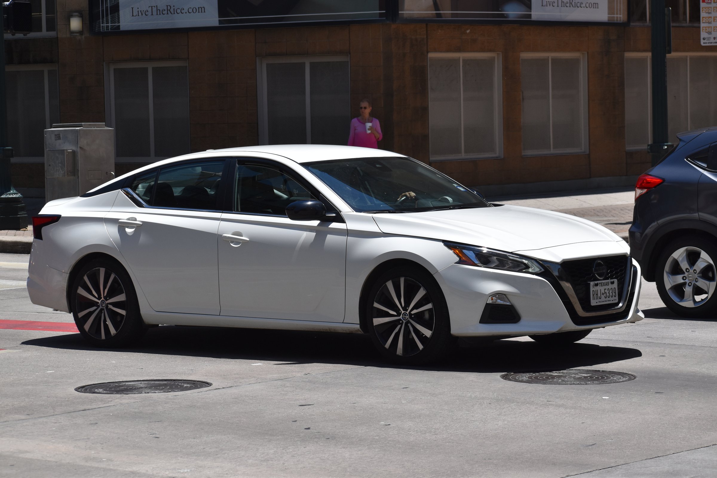 Houston, TX USA - 5/15/2024 - A portrait of a white Nissan Altima traveling down a highway in moderate traffic